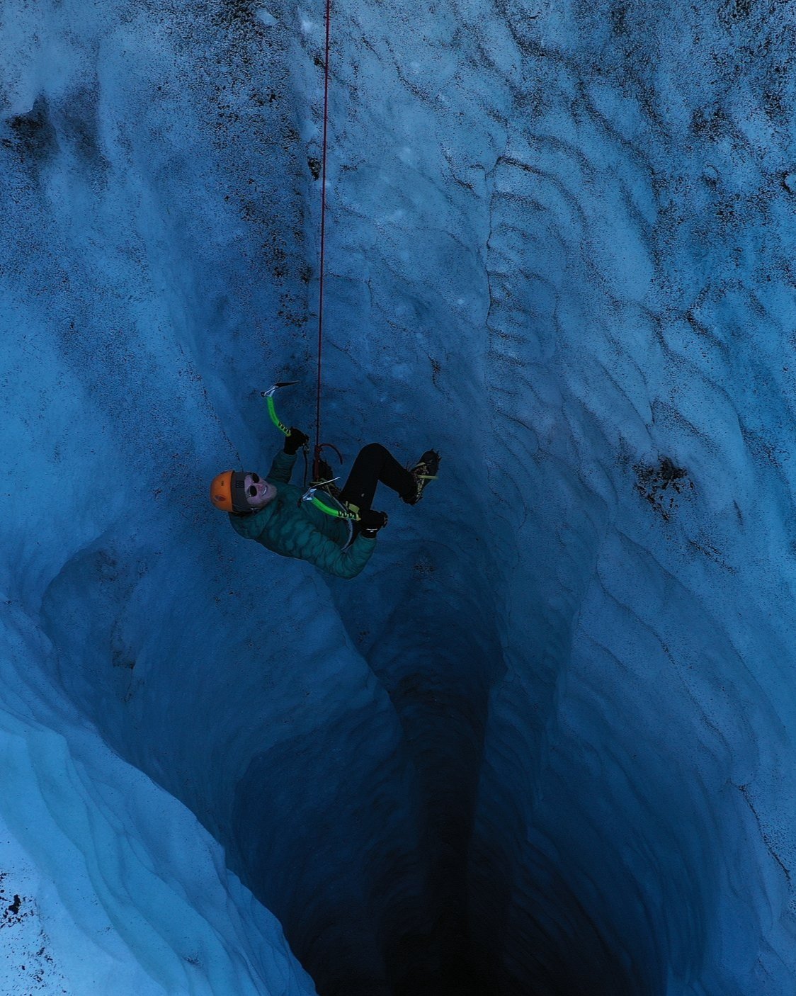 A climber hanging and enjoying the view of  a deep moulin at Sólheimajökull glacier.