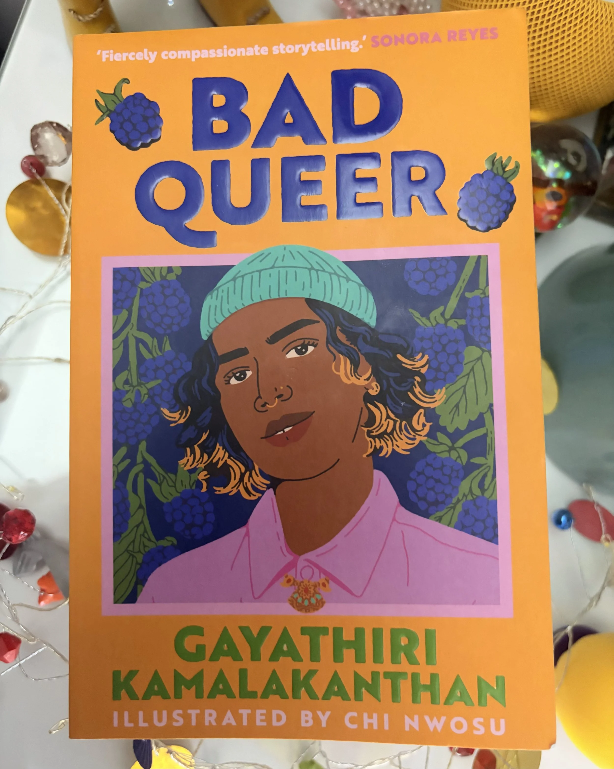 Bad Queer, sat amongst colourful objects