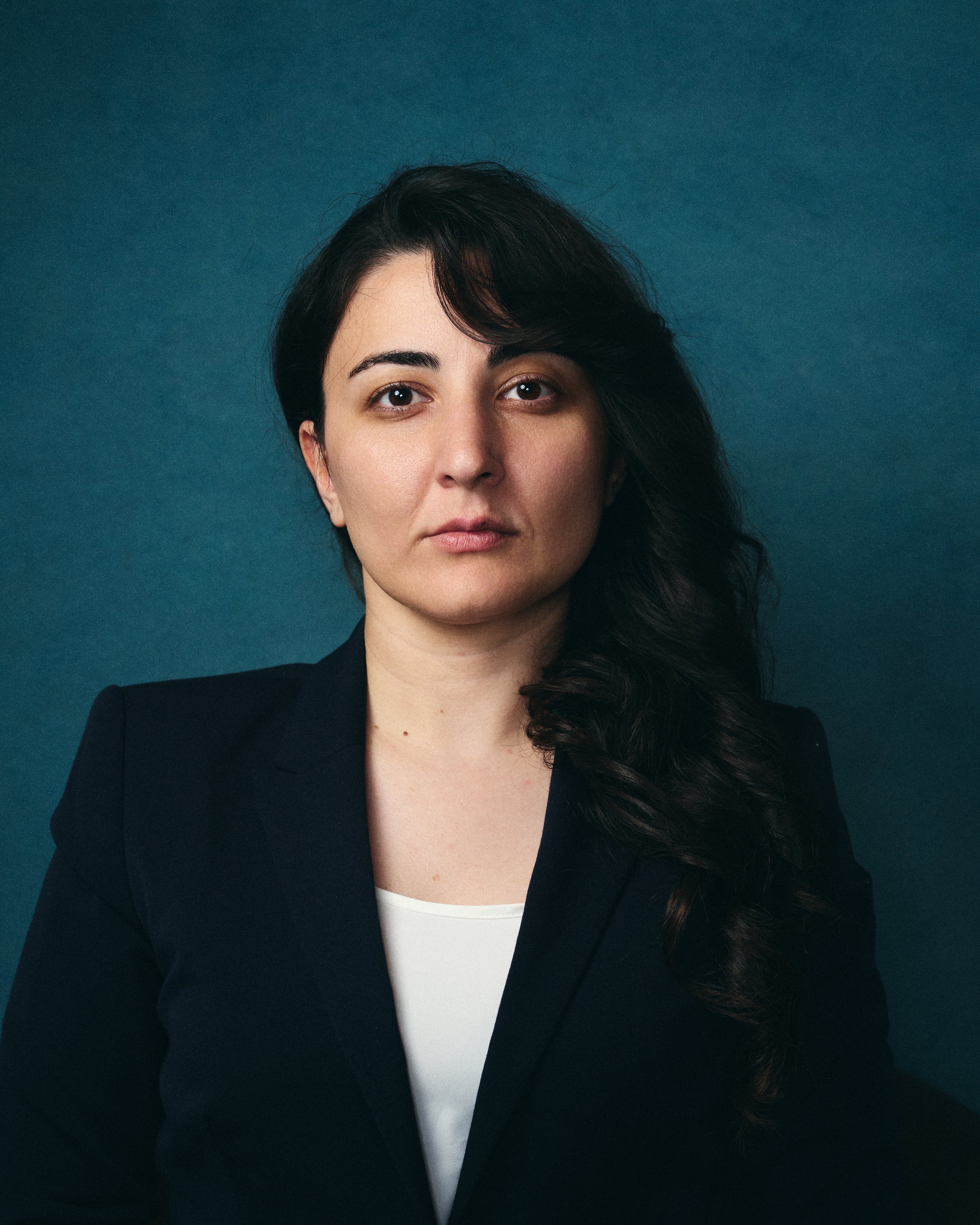 Portrait of Mahshid against a dark teal background.