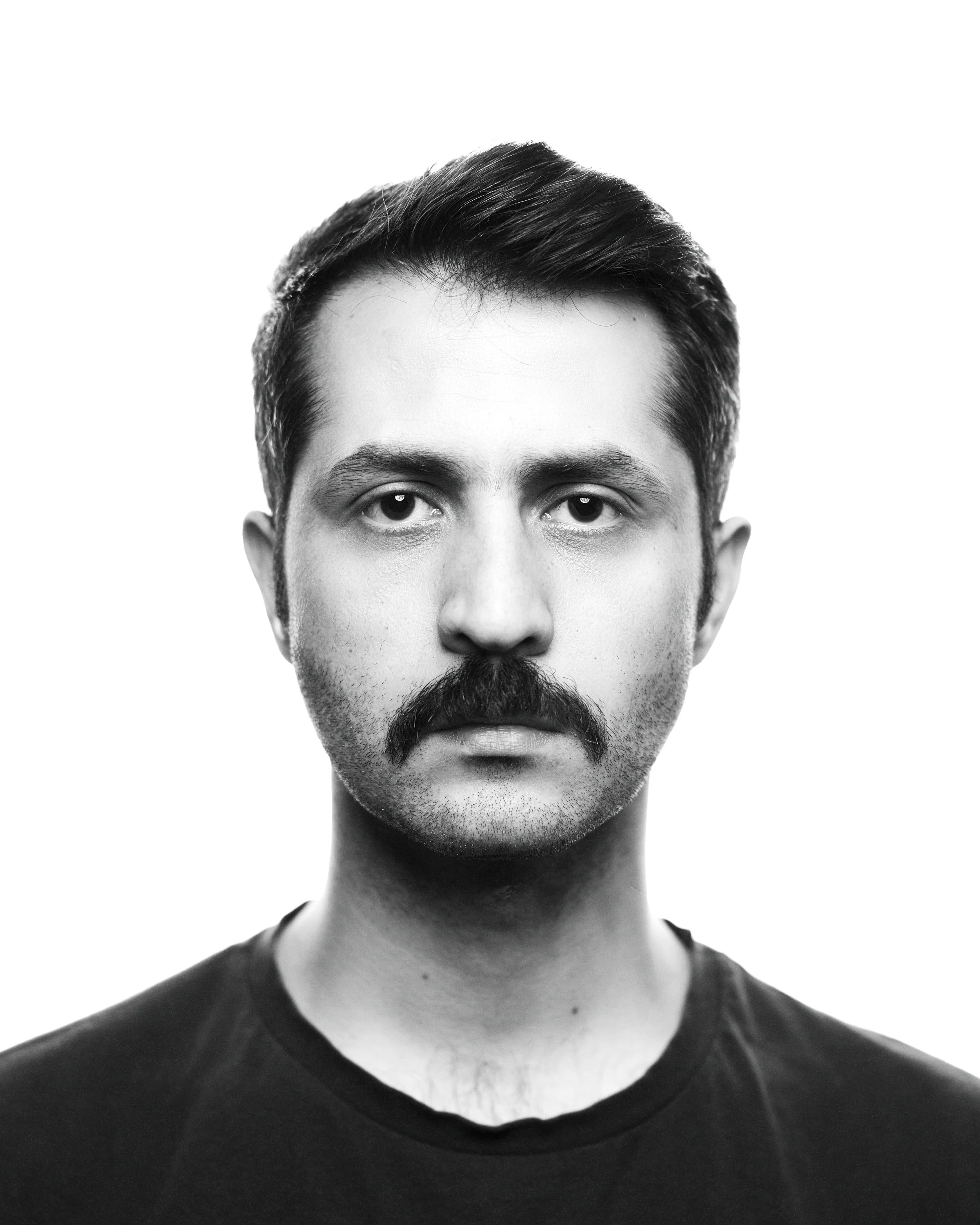 Black and white portrait of a man with a mustache and short hair, facing directly forward, with a serious expression.