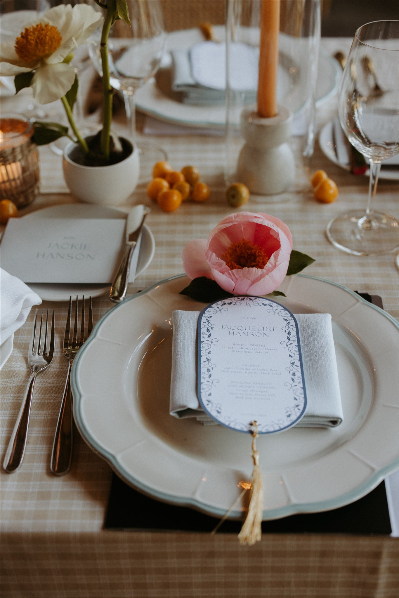 Wedding place setting with tasseled menu, scalloped plate, and pink poppy flower