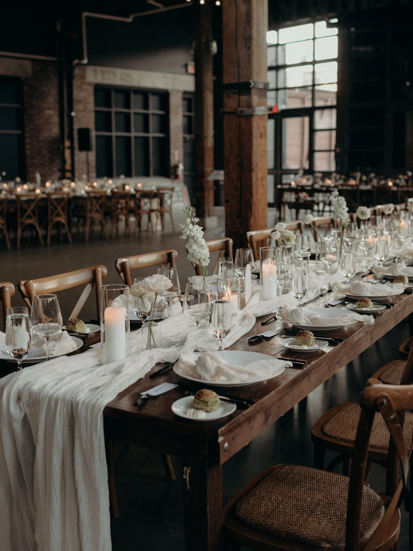 At Steam Whistle Brewing, Casey + Lucas wanted a reception that felt warm, unfussy, and deeply personal.

Soft runners, relaxed napkins, candlelight, and full bloom airy white florals. Just enough to create a mood that invites conversation, closeness