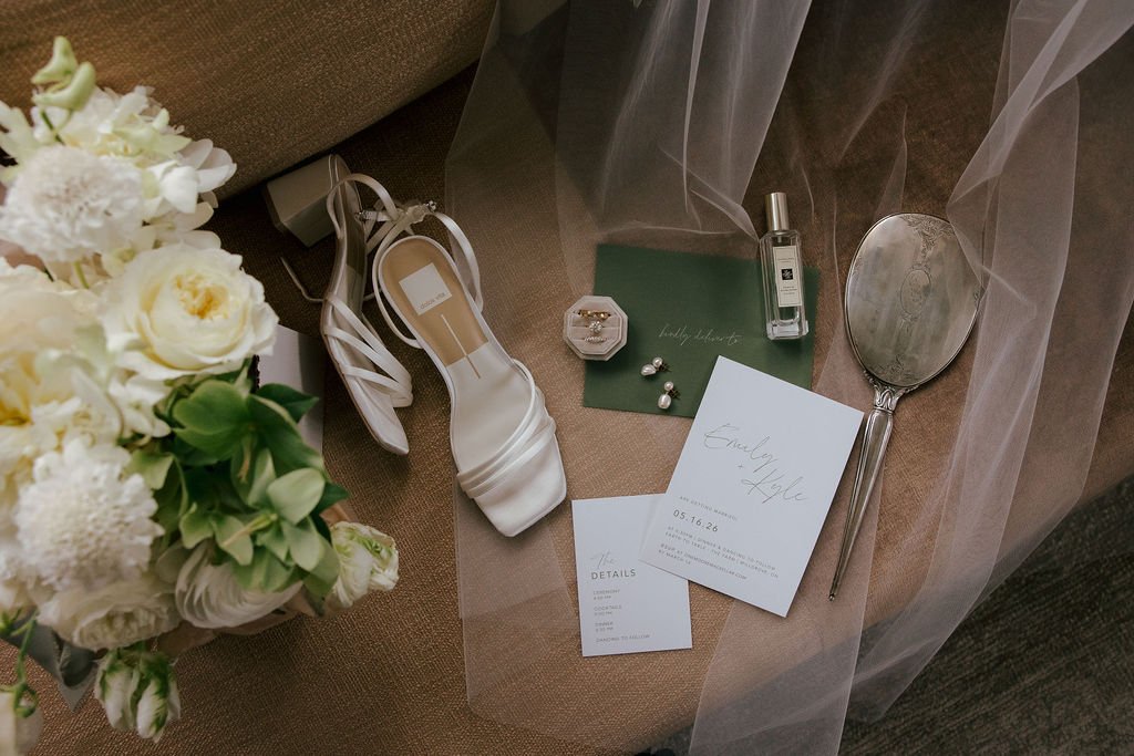 Flatlay of Dolce Vita bridal shoes, wedding invitation, and bouquet by Wild Vogel Works