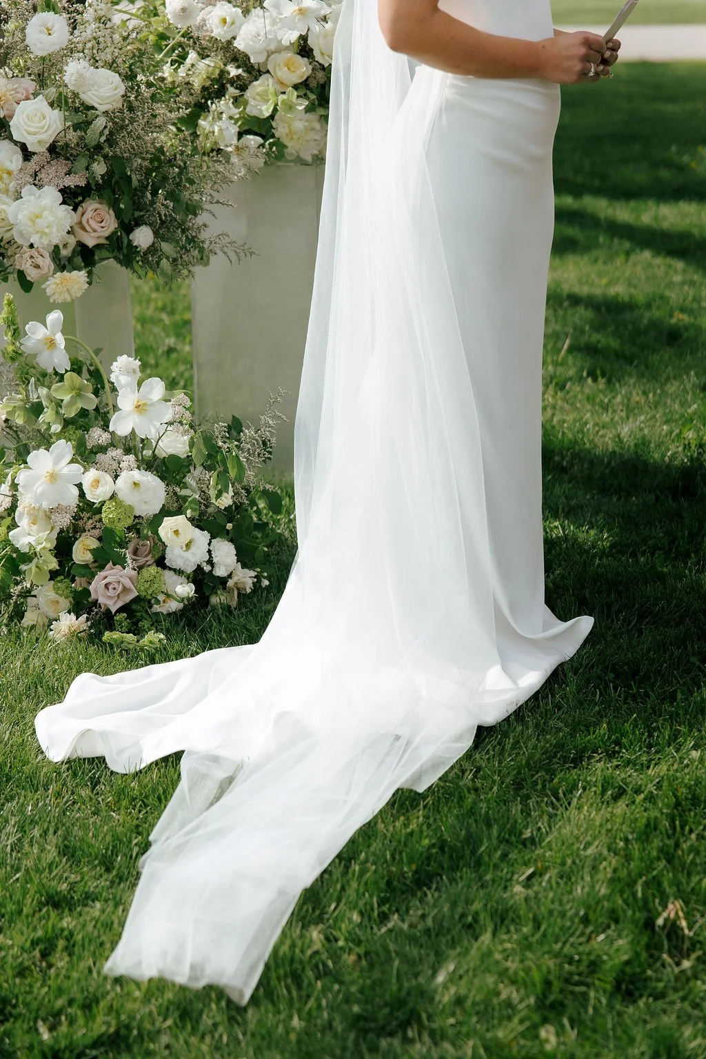 Close-up of bride's veil and dress train with white flowers