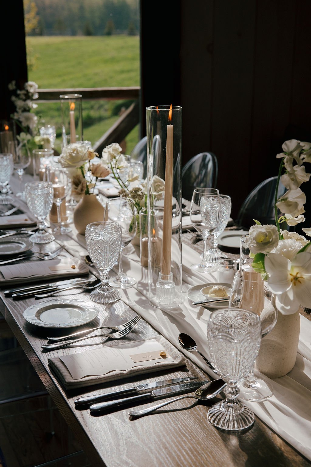 Wooden harvest table with white flowers and vintage glassware