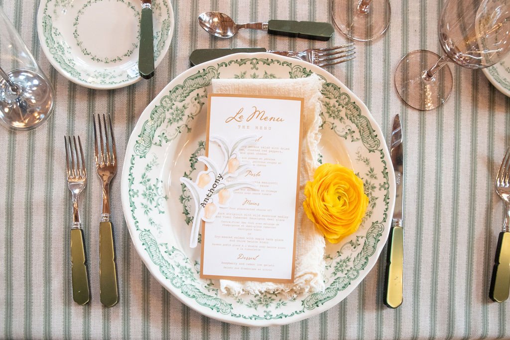Wedding place setting with vintage green dishware, linen napkin, and yellow rose