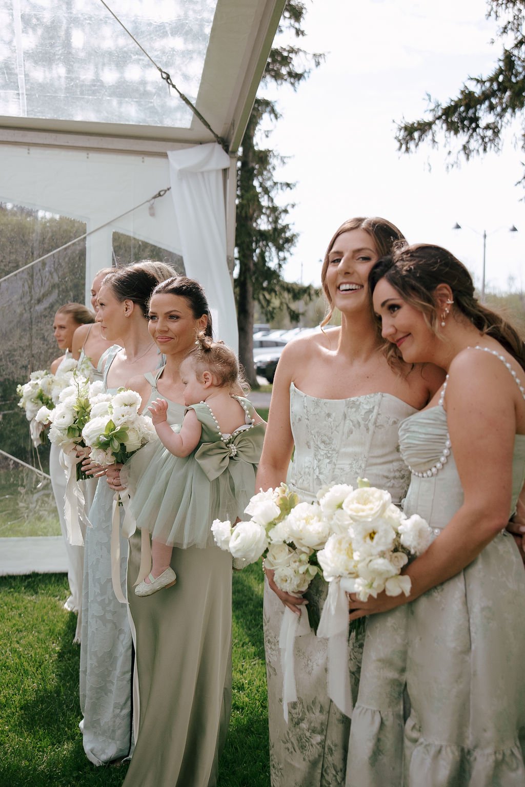 Bridesmaids wearing pastel green gowns and holding white bouquets