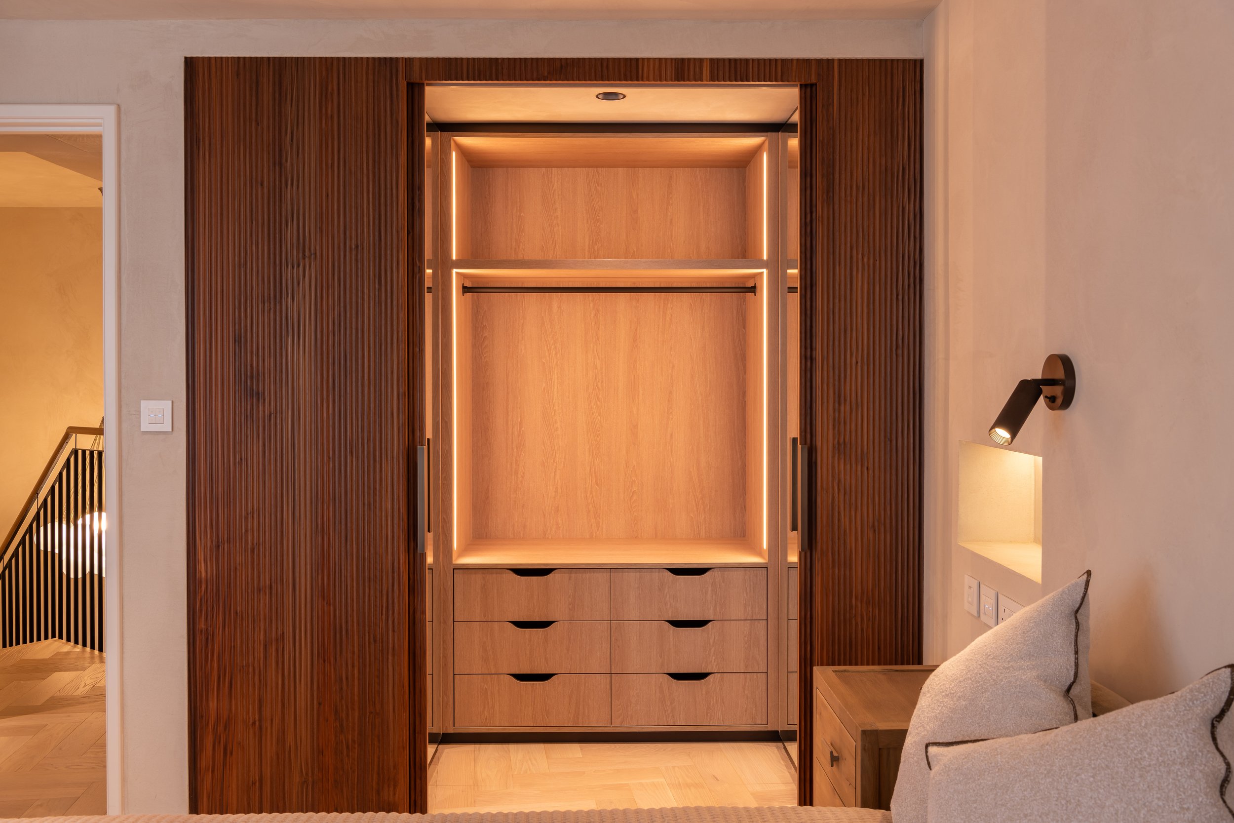 Empty modern wardrobe with wooden finish, built-in drawers and clean design in a contemporary bedroom.