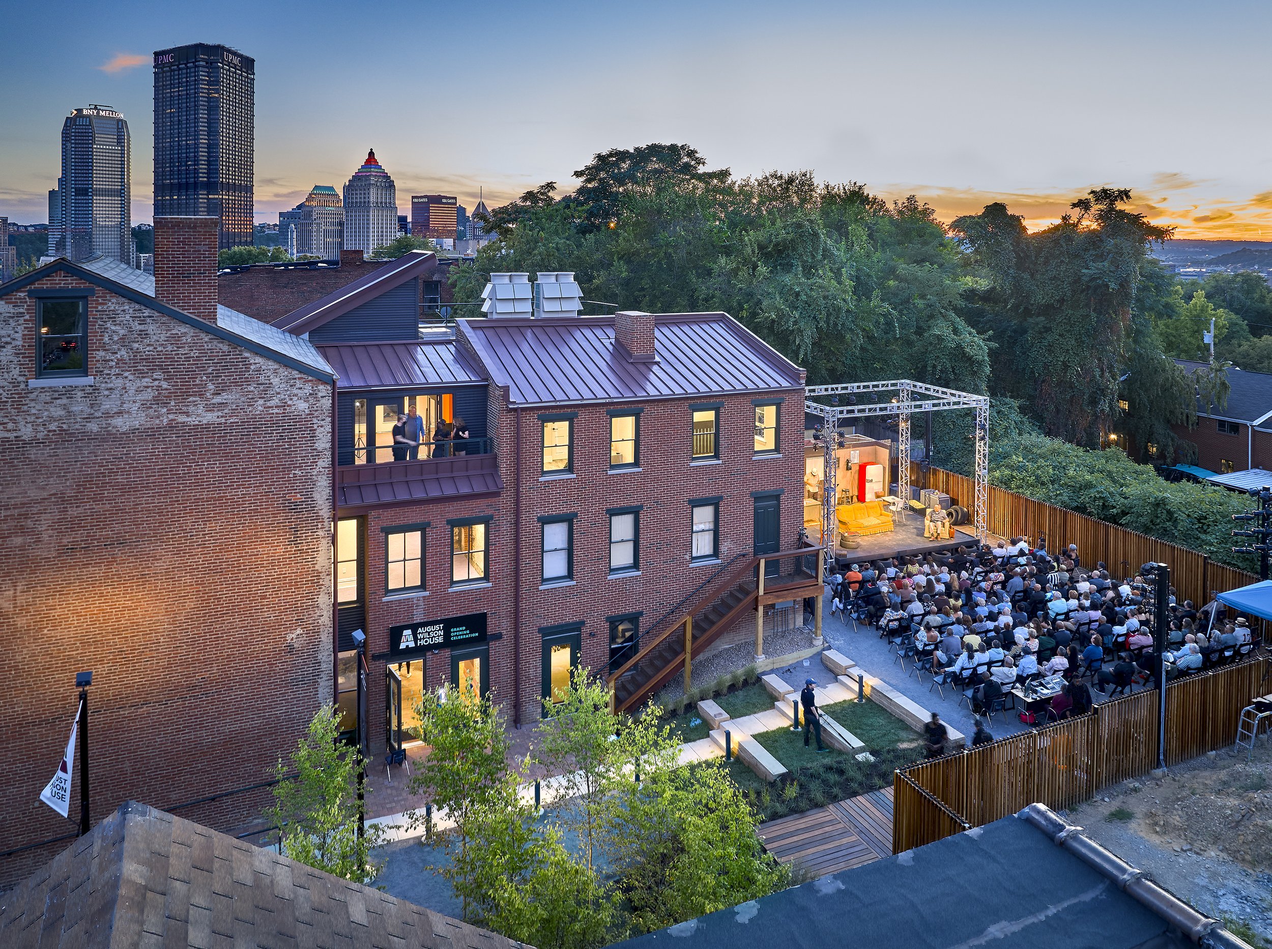 Aerial view looking into rear yard during an evening performance. Light and sound poles integrated into the fence allow for flexibility in event layout