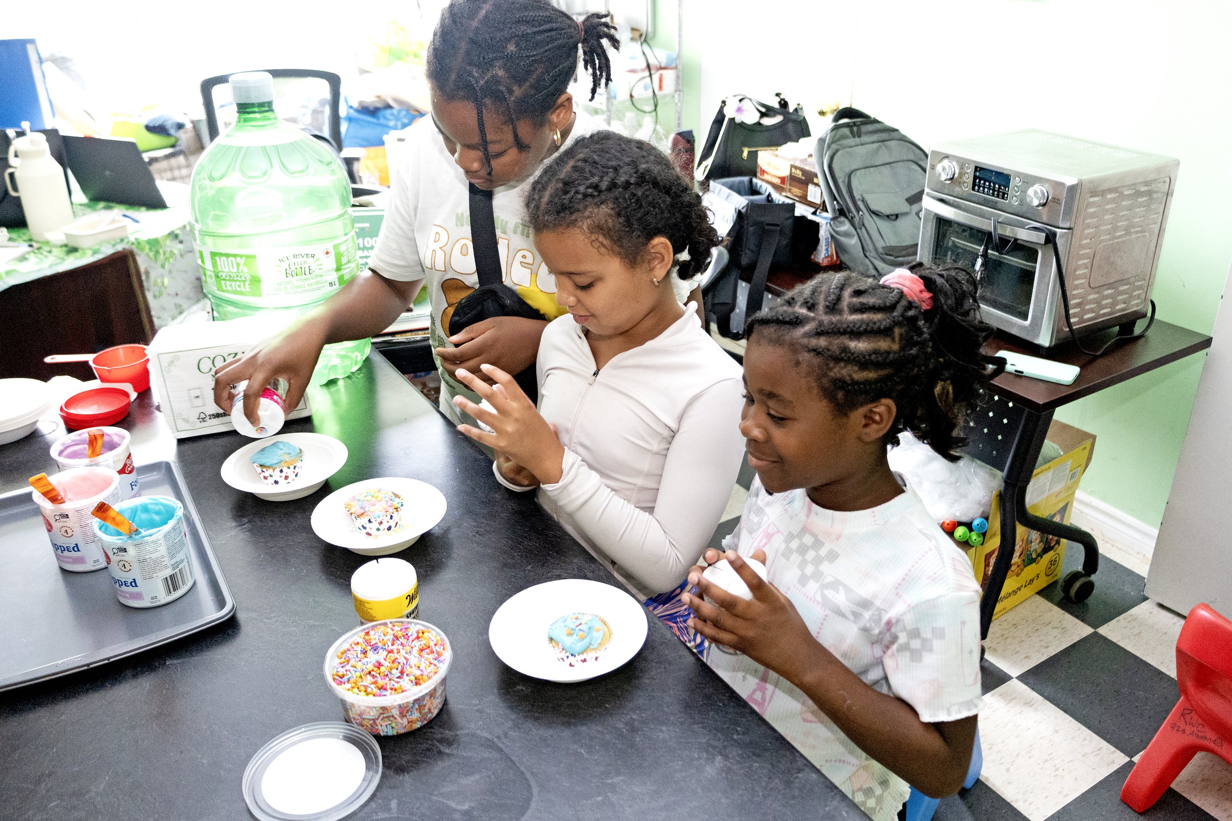 Three summer camp children decorating cupcakes