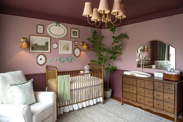 Vintage style decorated baby nursery with a white recliner, gold crib, and a brown dresser.