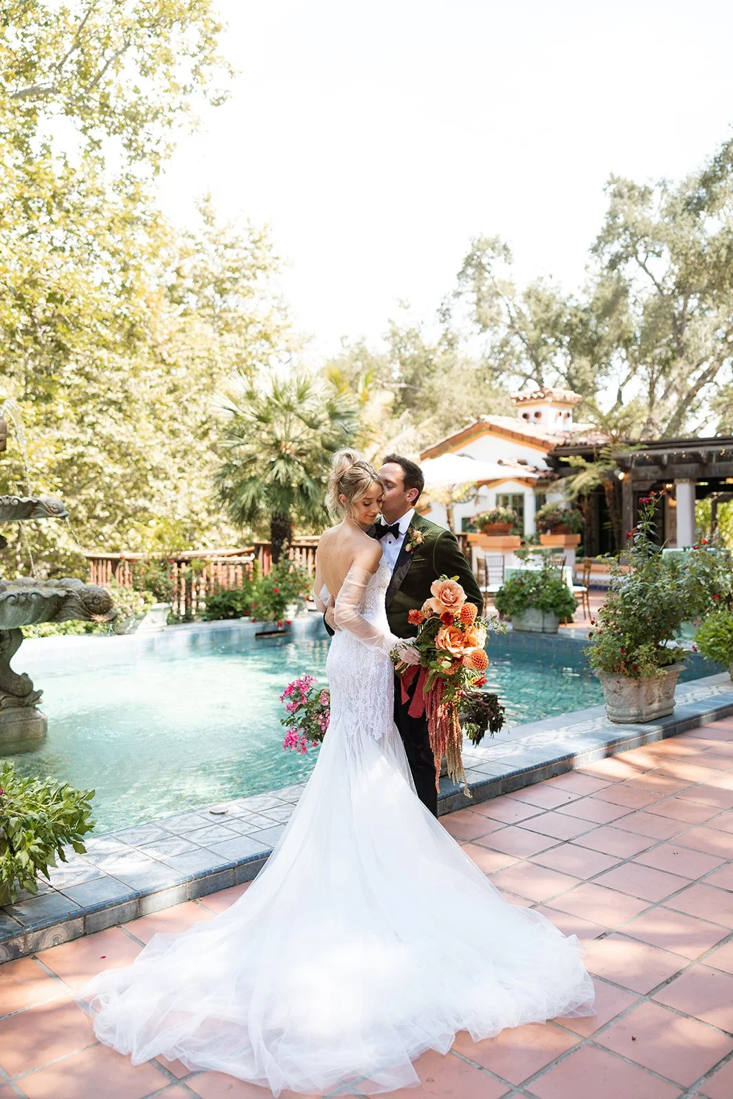 Bride and groom kissing by a pool at a wedding reception outdoors