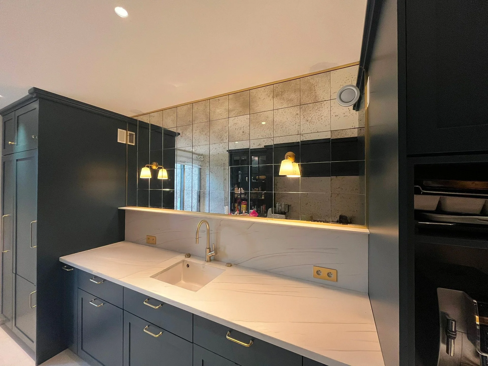 Cuisine moderne avec un miroir piqué vieilli, posé en damier, dans une cuisine avec design intérieur style art déco sur Marseille