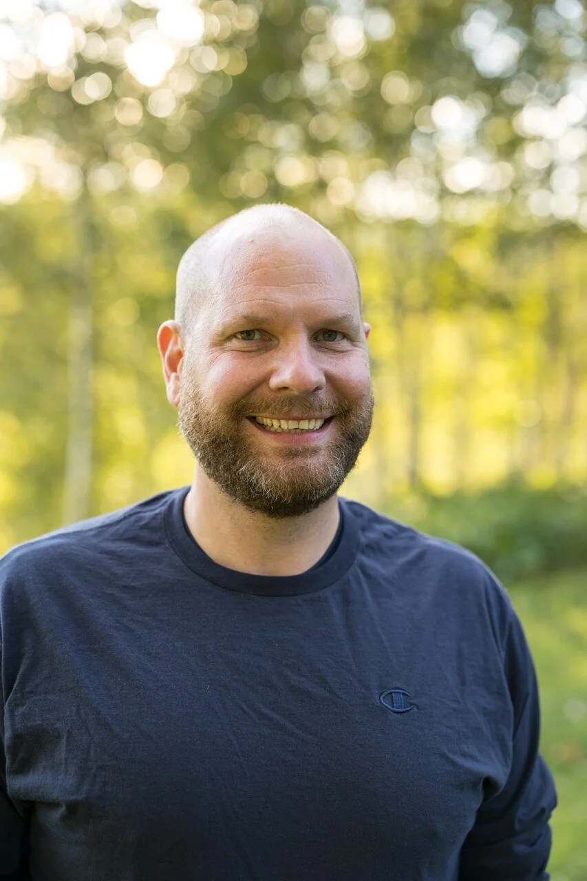 photo of teacher Matt Camp smiling at the camera. Young, white man with a beard and a blue shirt