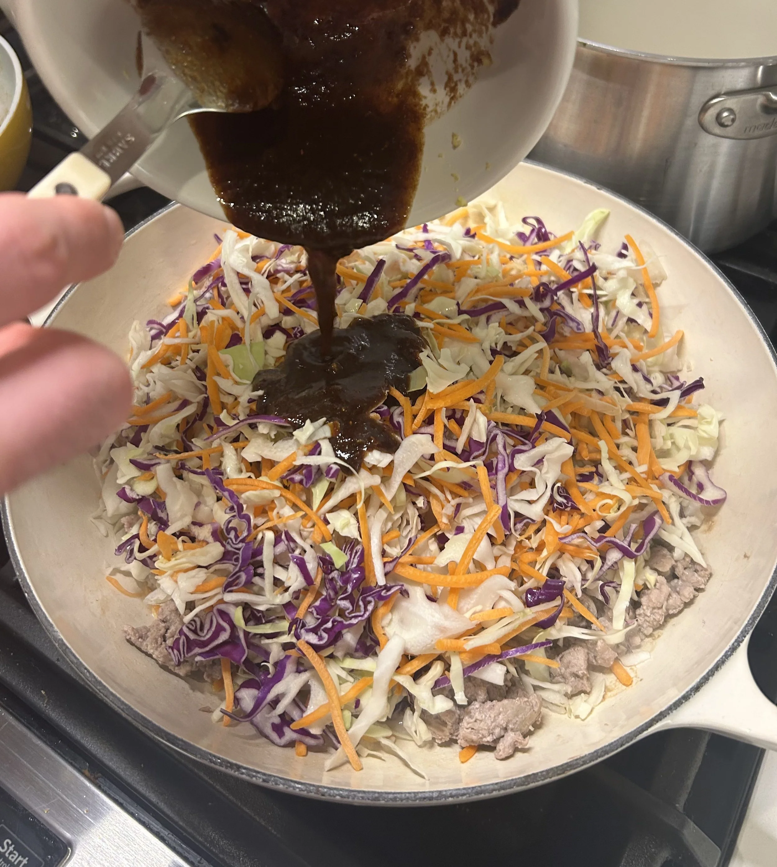 the sauce being added to the egg roll in a bowl stir fry dish