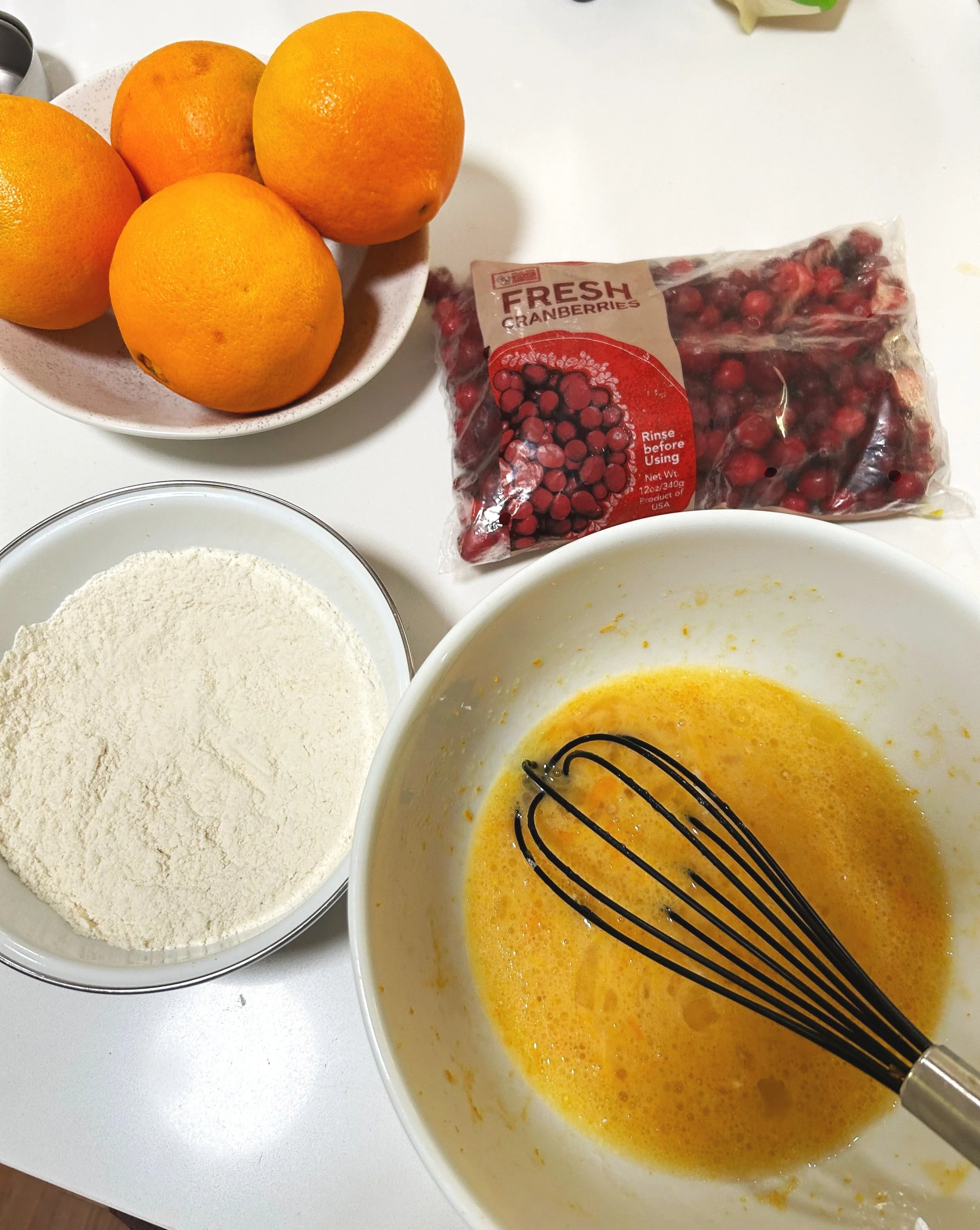 the separated dry and wet ingredients needed to make orange and cranberry loaf cake