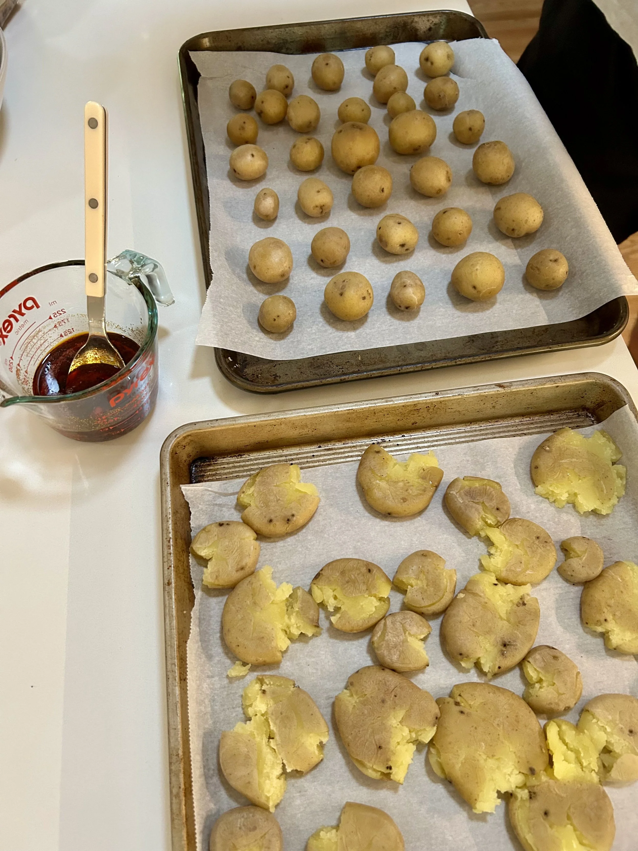 Potatoes in the process of being smashed in step 4 of this chili oil smashed potatoes recipe