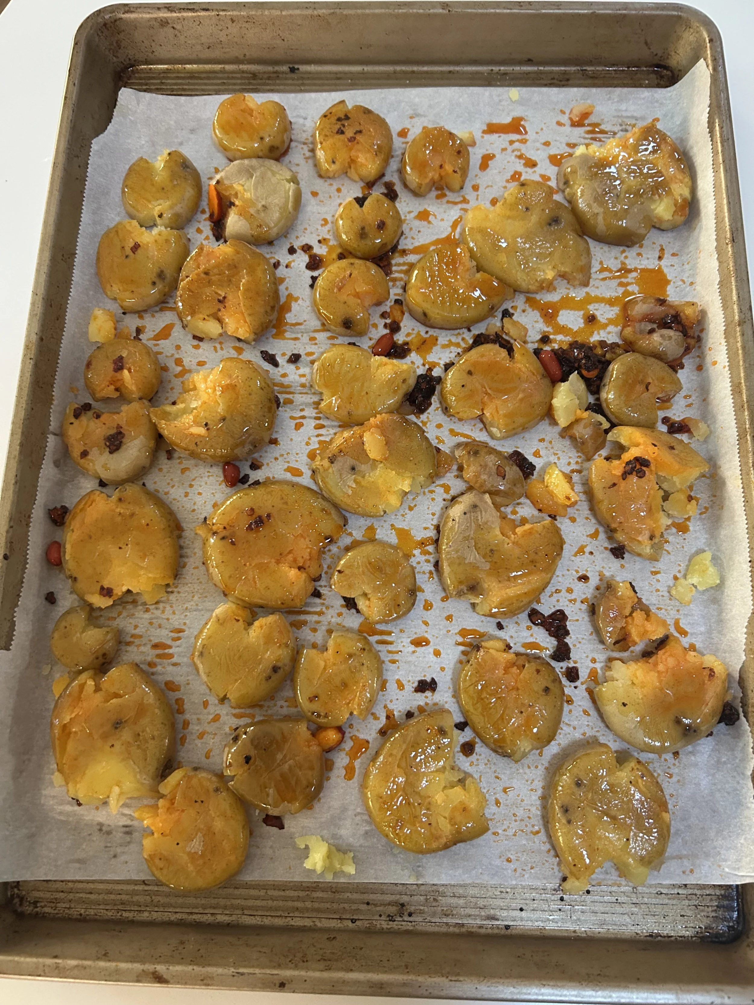 Potatoes smashed and coated in oil, ready to roast in the oven and become crispy