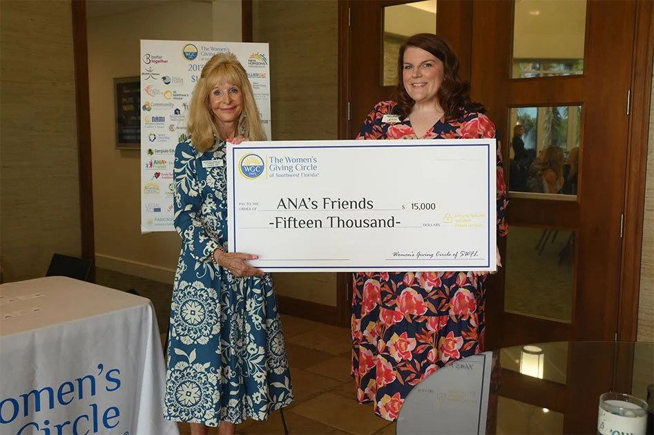 2 Women holding a large check from "The Women's Giving Circle" to ANA's Friends