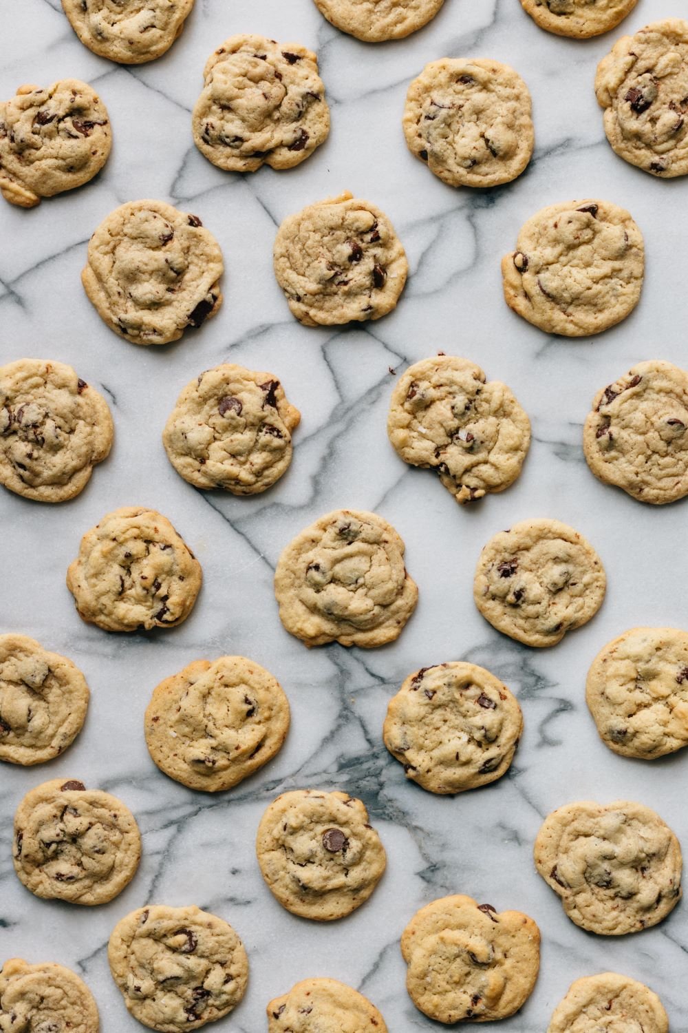 Freshly baked chocolate chip cookies on a marble surface.