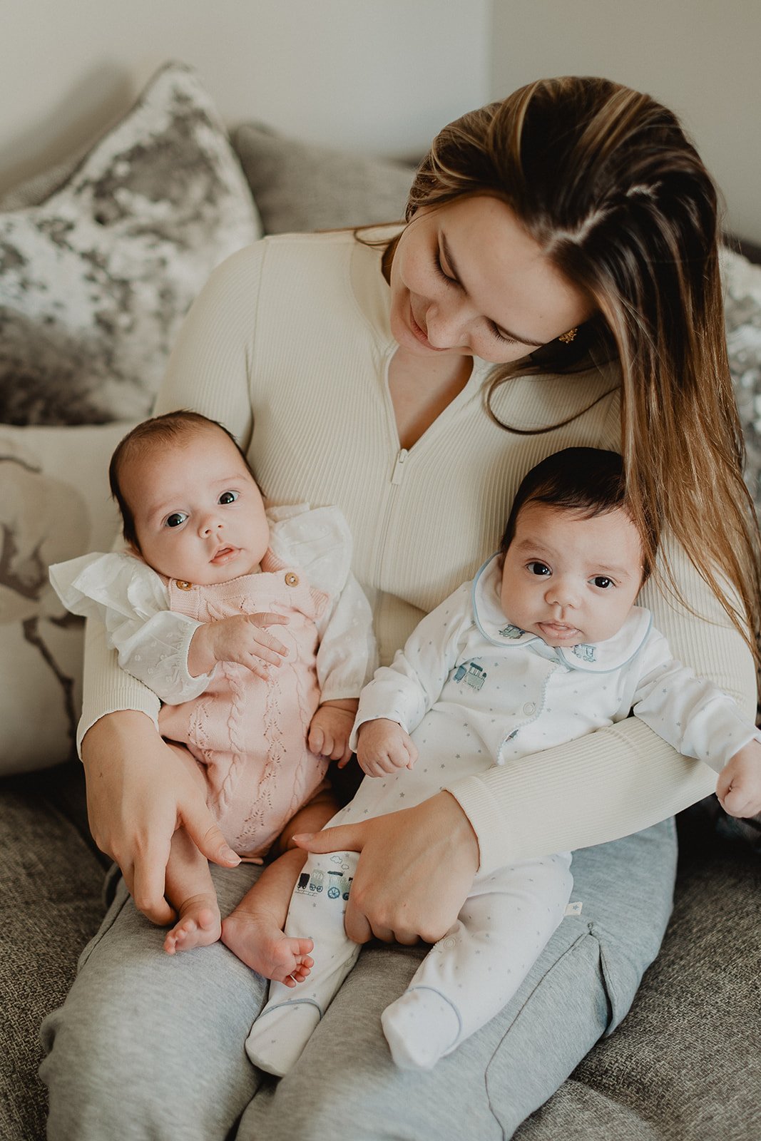 Newborn photography session with mum sat holding twin boy and girl.
