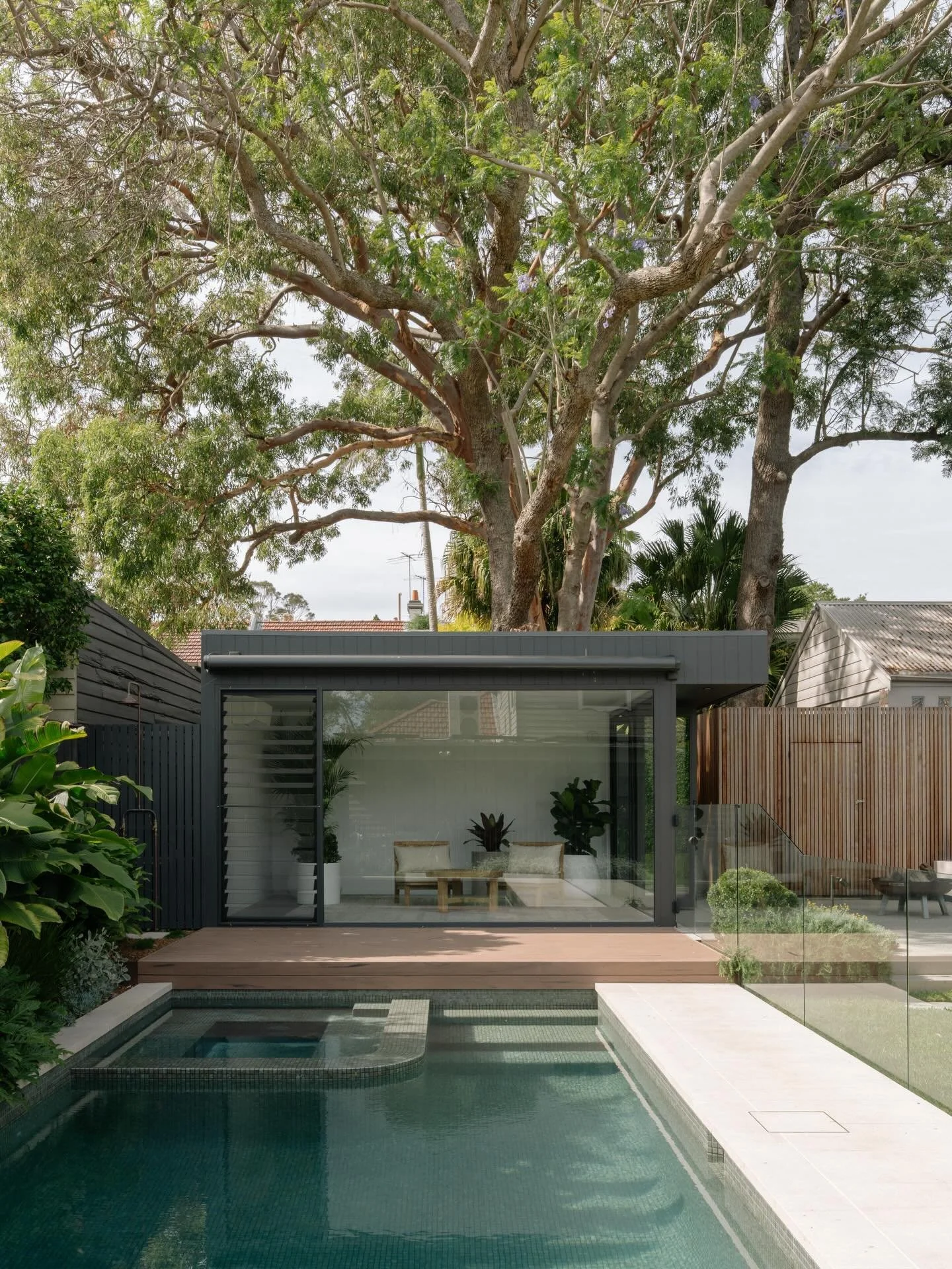 Sleek pool house with attached timber batten storage shed &amp; fire pit area, nestled in below tree canopy to anchor pool &amp; backyard.