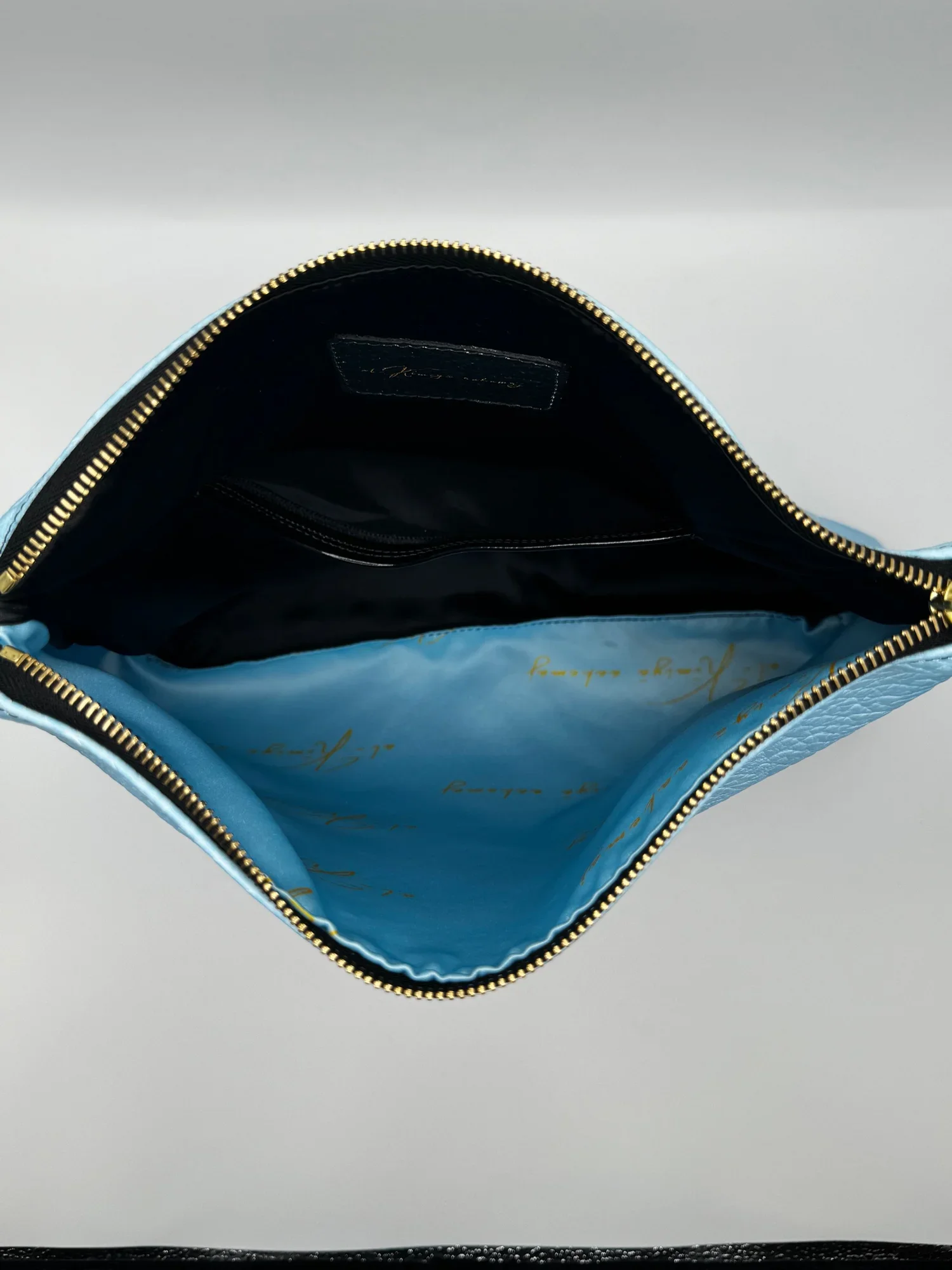 photo of the satin printed interior lining of a leather Clutch purse, detailed with a gold zipper