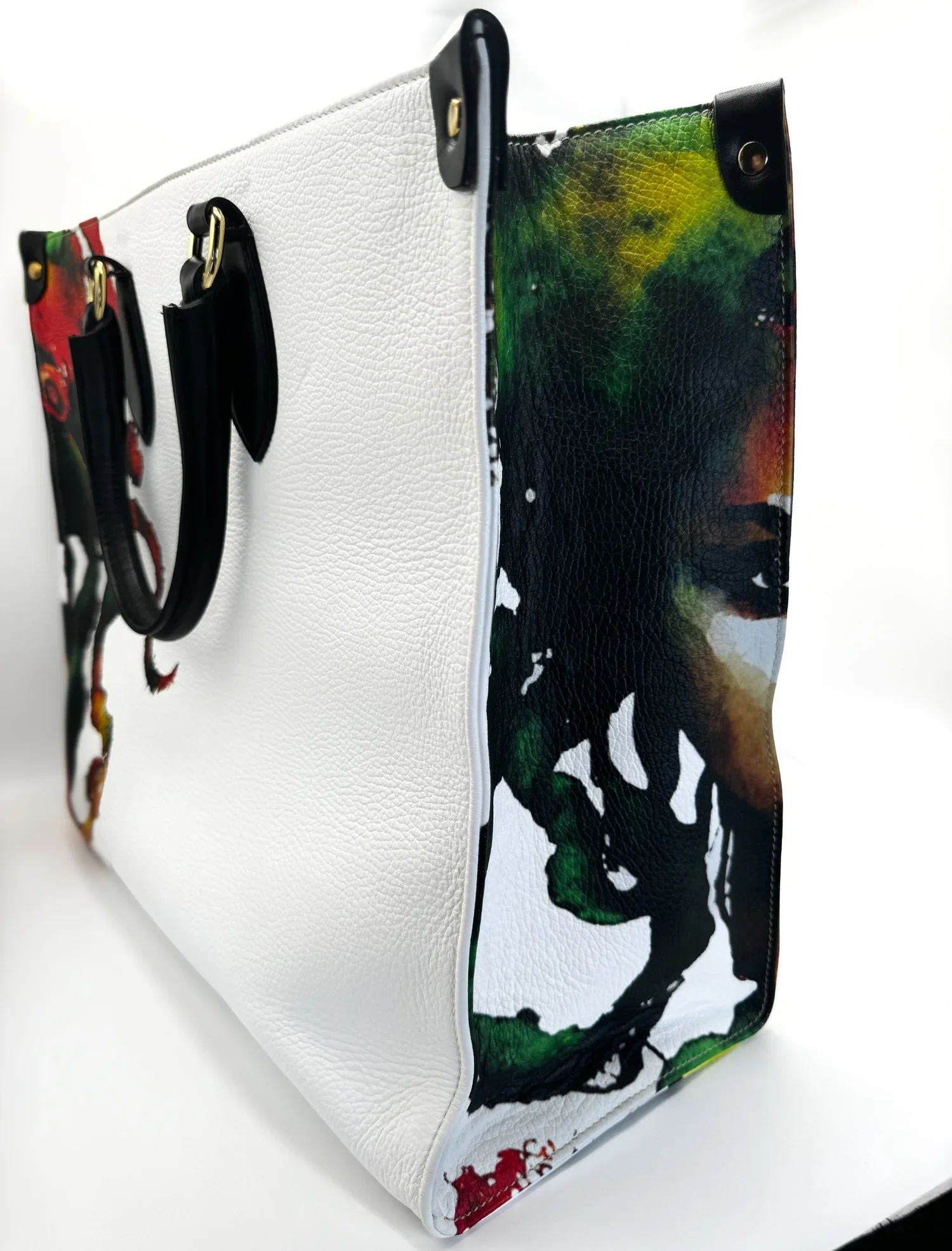 Close up photo of a large textured white leather shopper bag, with a unique watercolor image on the front and side panels of the bag.