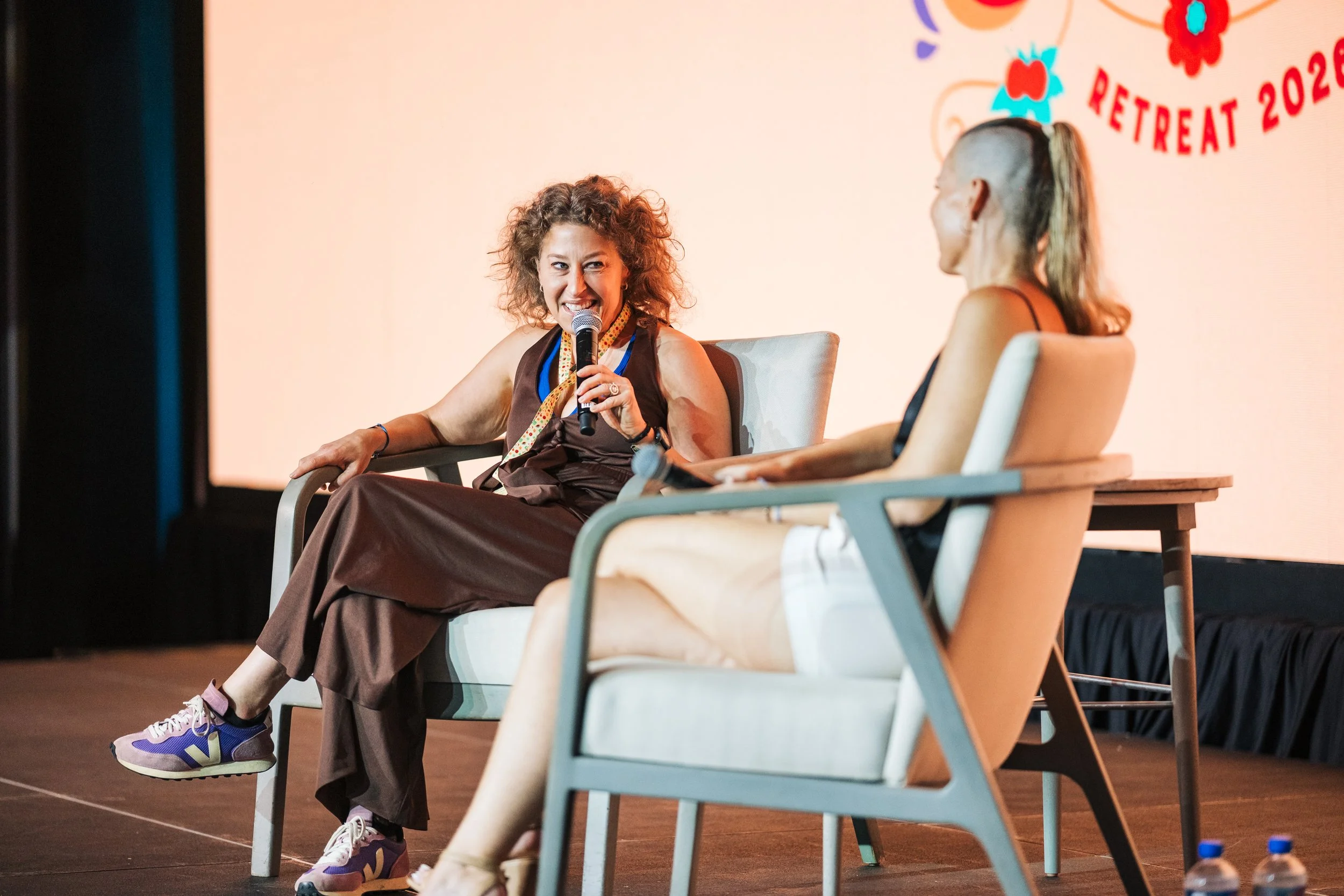 Rachel Fleischman speaking onstage at a wellness retreat
