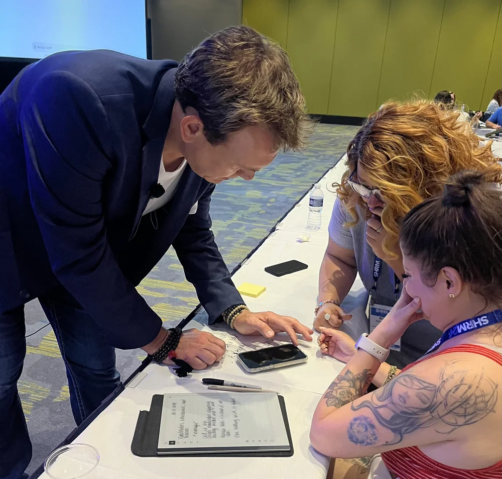 Mitch Mitchem coaching two professionals hands-on at a workshop table.