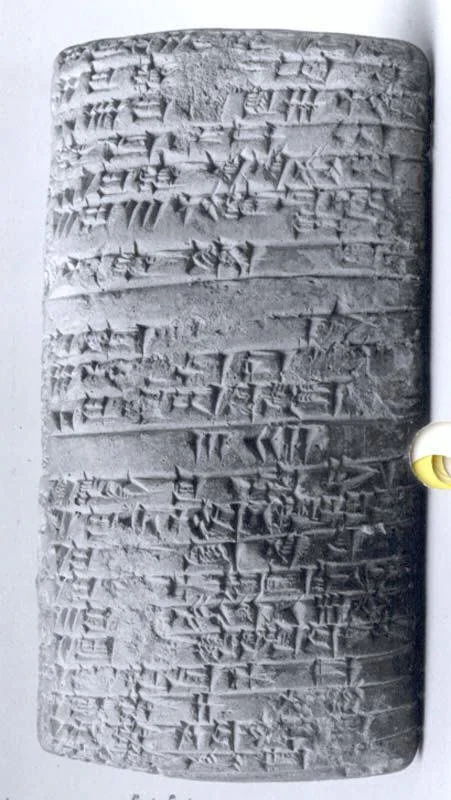 A close-up of an ancient clay tablet with cuneiform script, showing detailed wedge-shaped impressions.