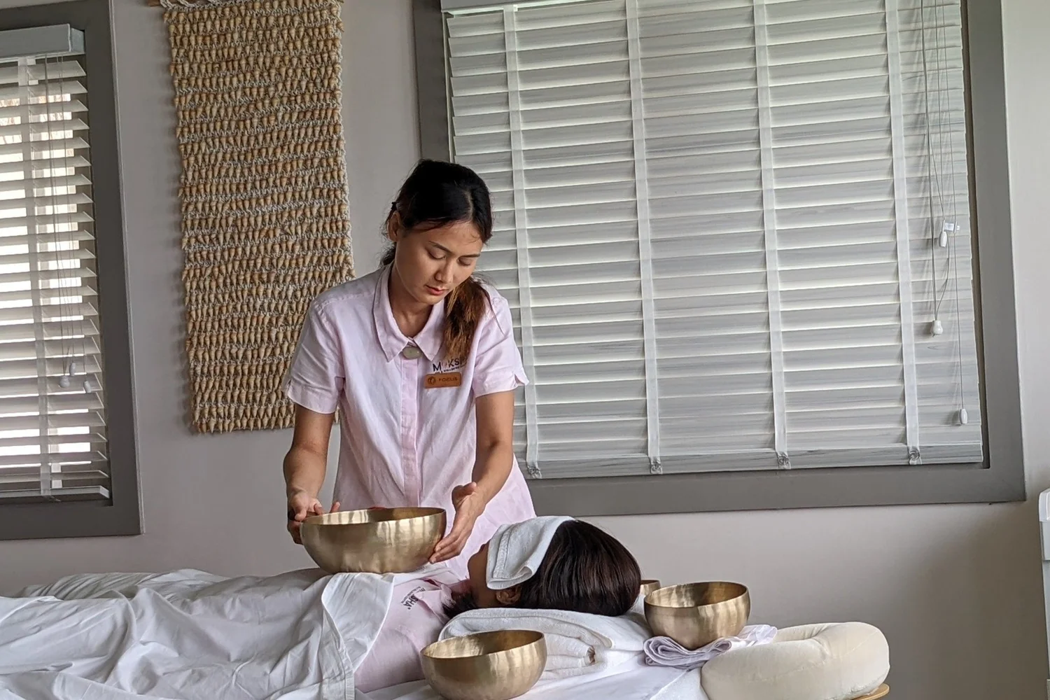 Hands playing singing bowls with mallets during a serene sound healing session.