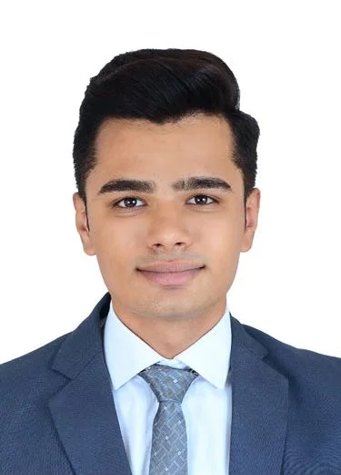 A young man with dark hair, wearing a suit and tie, posing against a plain white background.