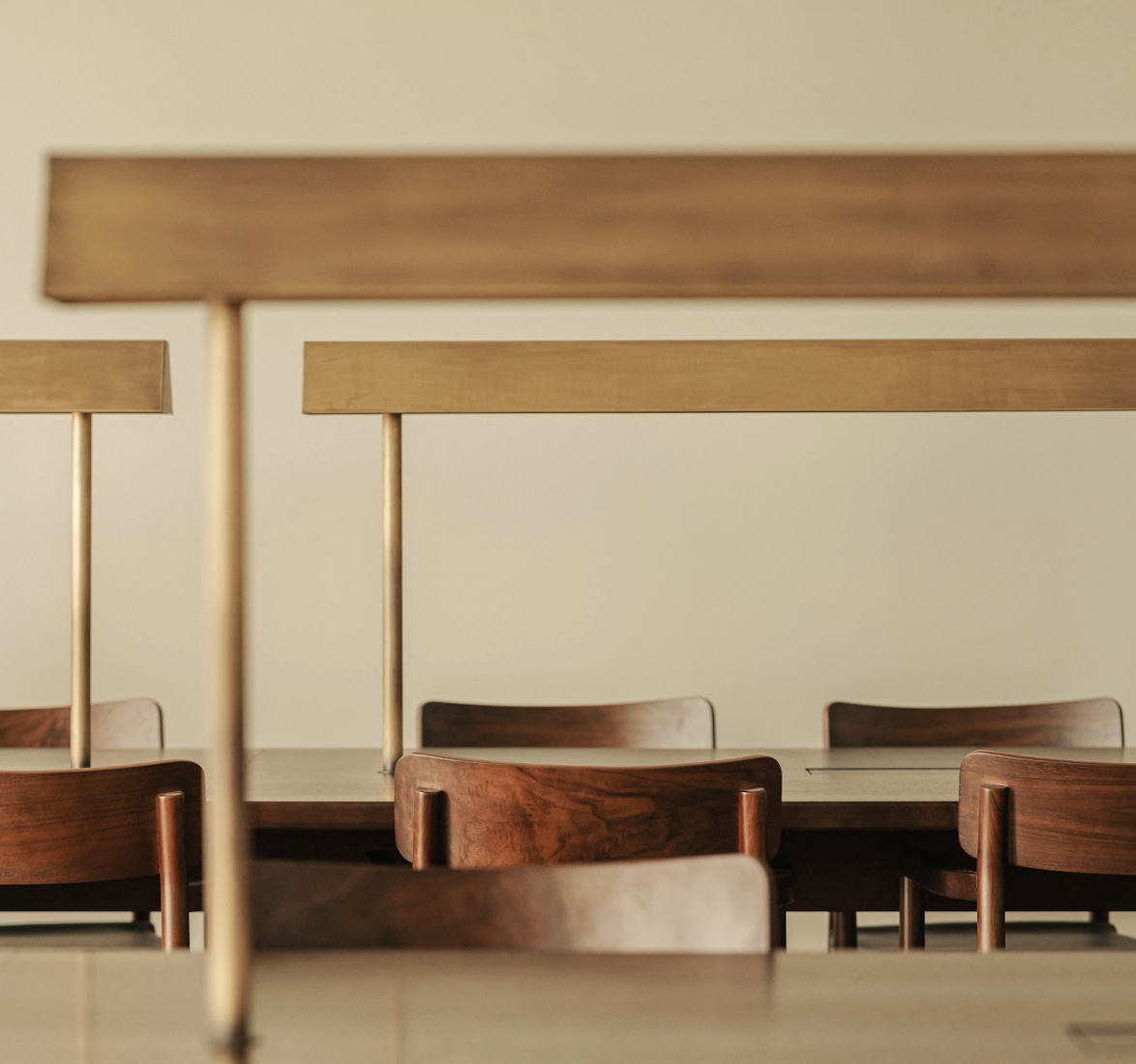 Mehrere Holztische und -stühle in einem Raum, durch einen Holzrahmen im Vordergrund sichtbar.