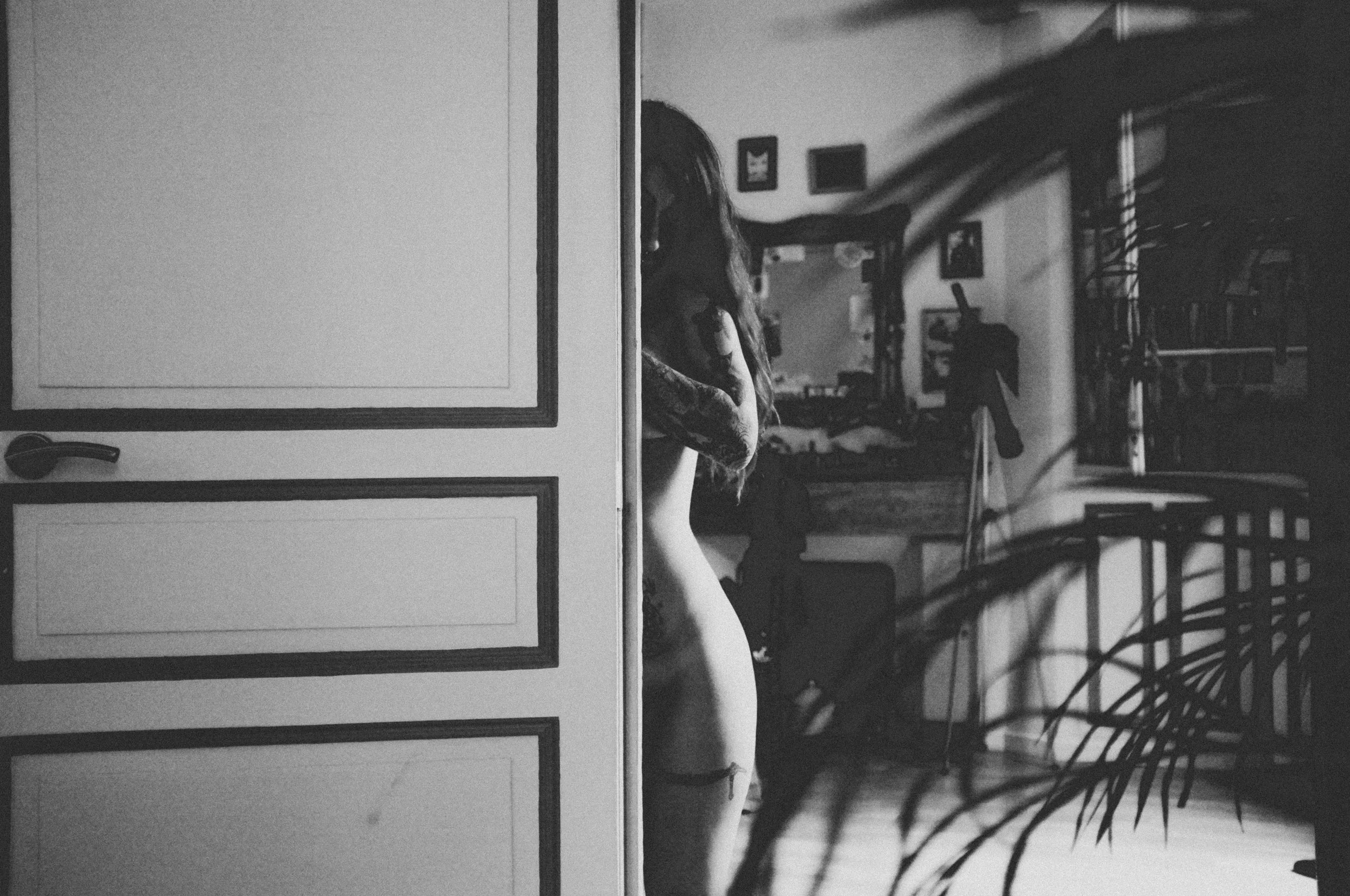 black and white picture of woman standing by wall in sexy manner