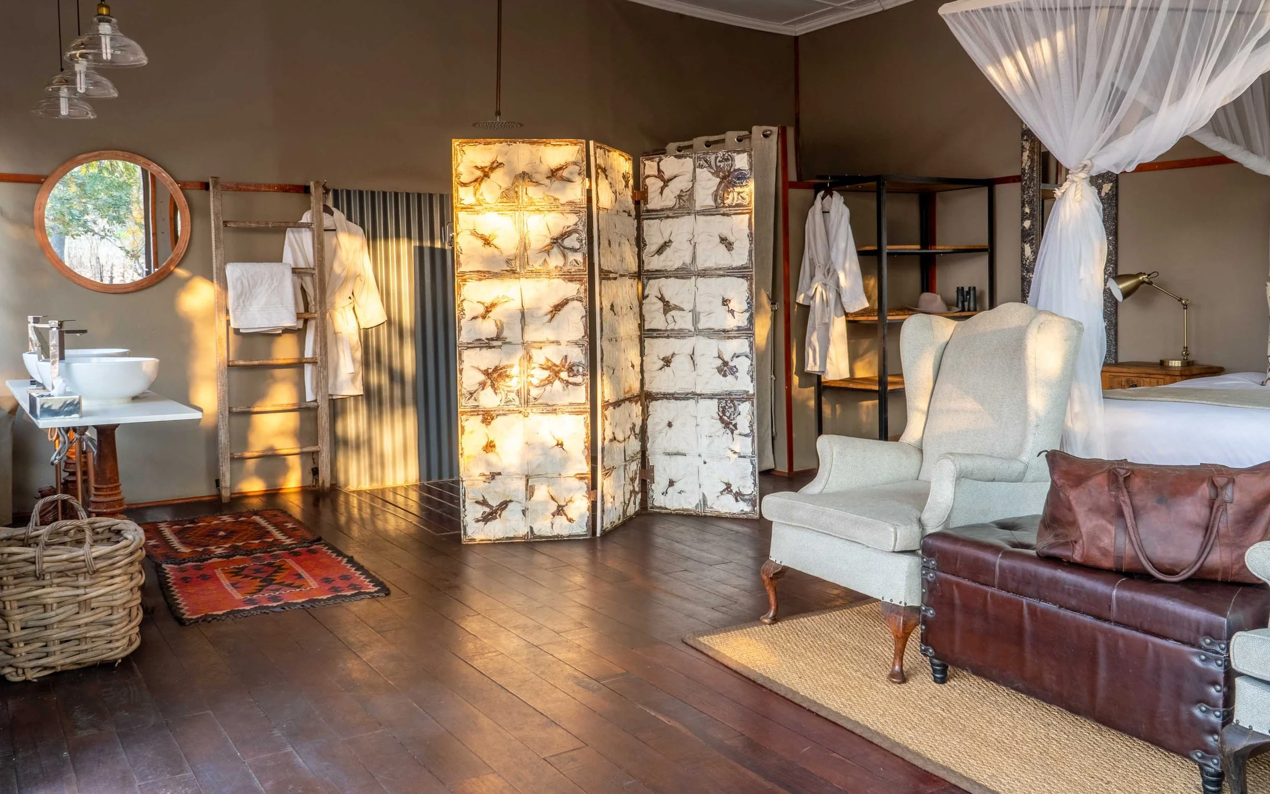 Bedroom with a washbasin, folding screen and wingback chair at Khulu’s Retreat
