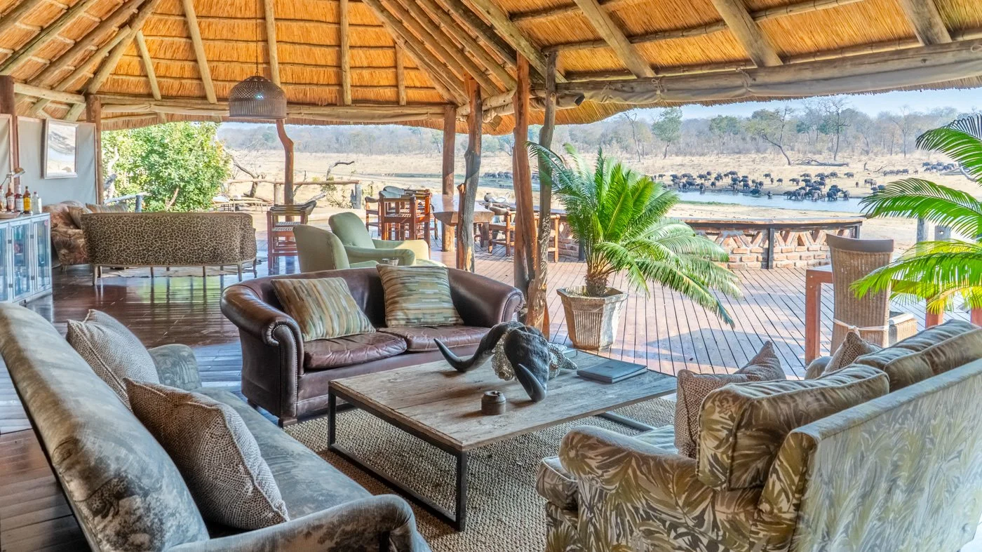 Khulu Bush Camp’s thatched lounge overlooking buffalo at the waterhole.