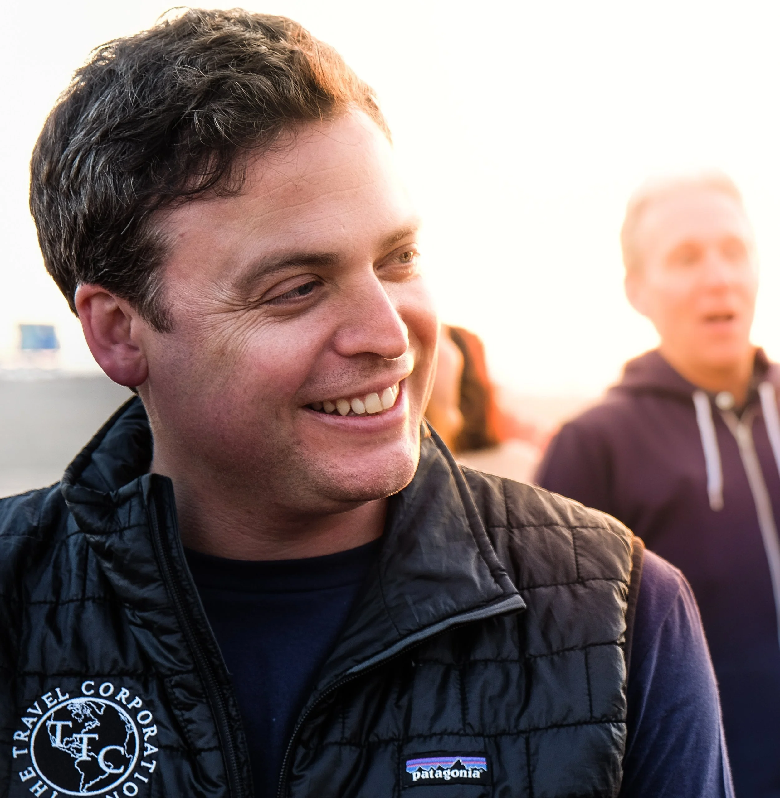 Smiling man wearing a black Patagonia vest outdoors.