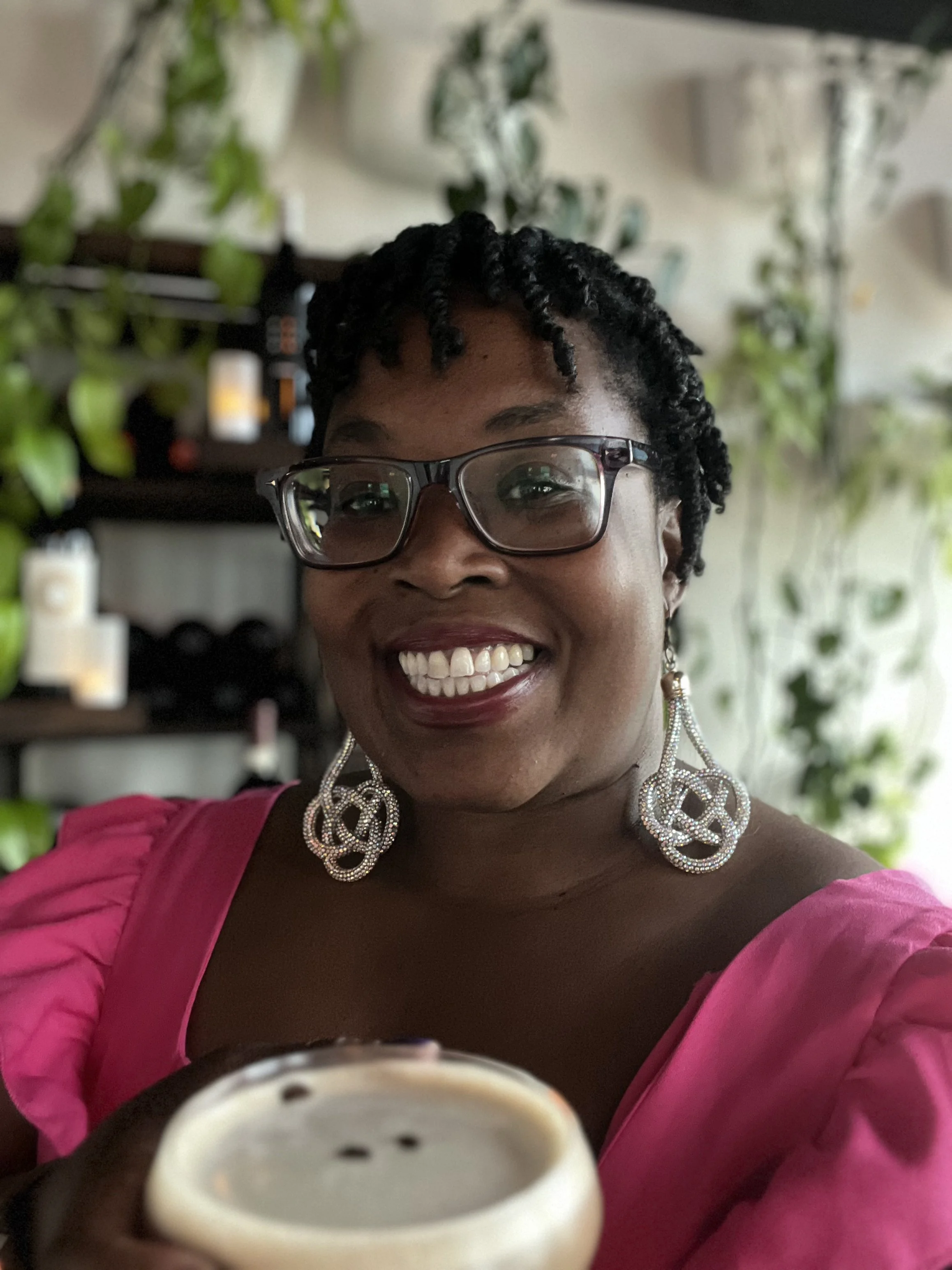 Leslie, owner of A Vibe Called Fest in a pink dress with a martini