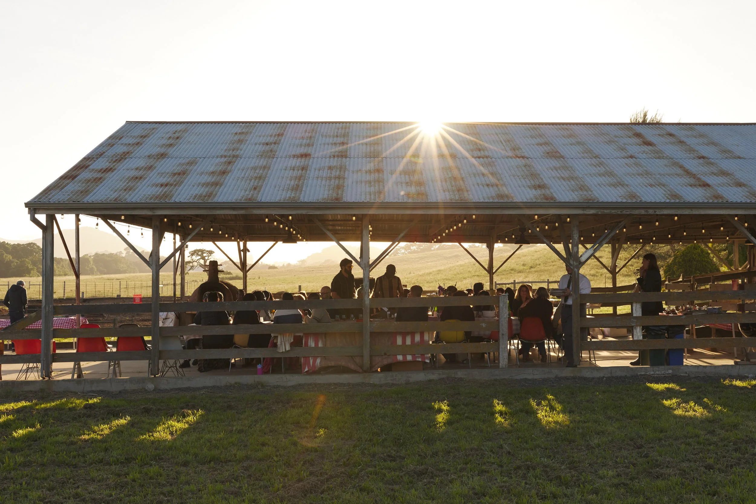 Image showing a group dinner in a rustic barn at the Eames Ranch during sunset