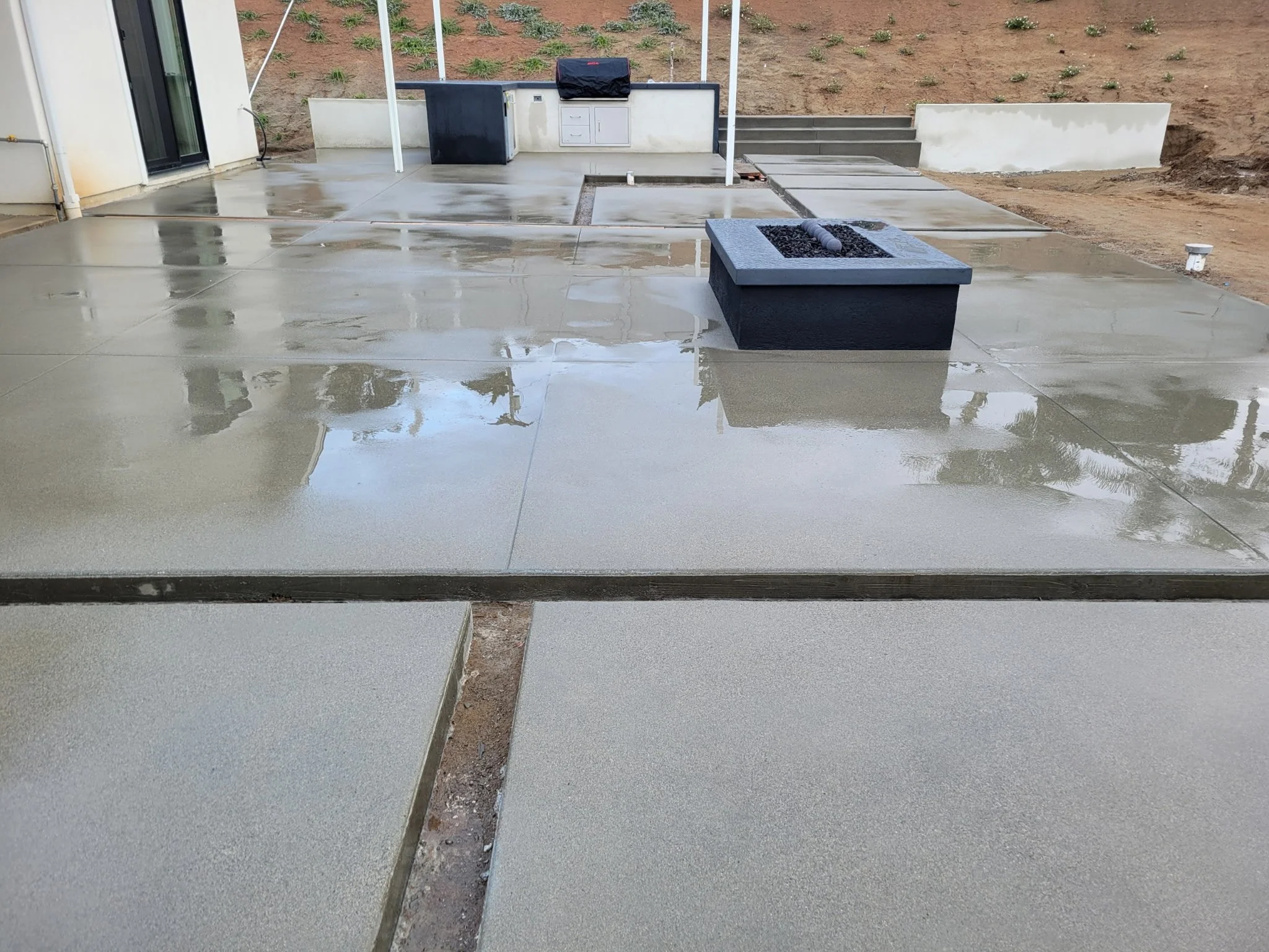 Custom backyard concrete installation connecting home patio door to outdoor living space, designed for durability, drainage, and modern hardscape aesthetics.