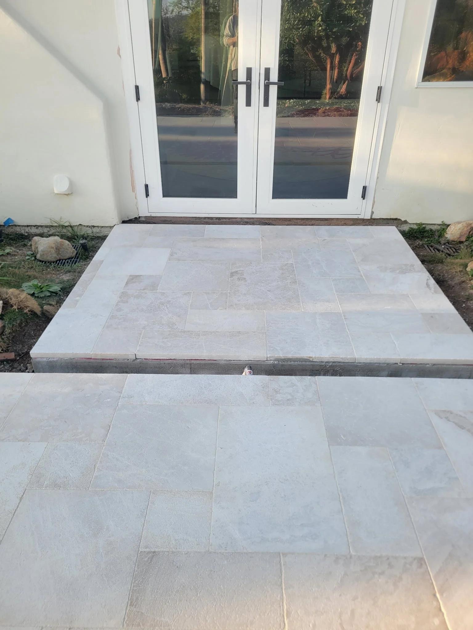 Newly installed residential concrete patio entryway leading from backyard door, professionally designed and poured by our hardscape team for a clean, durable outdoor space.