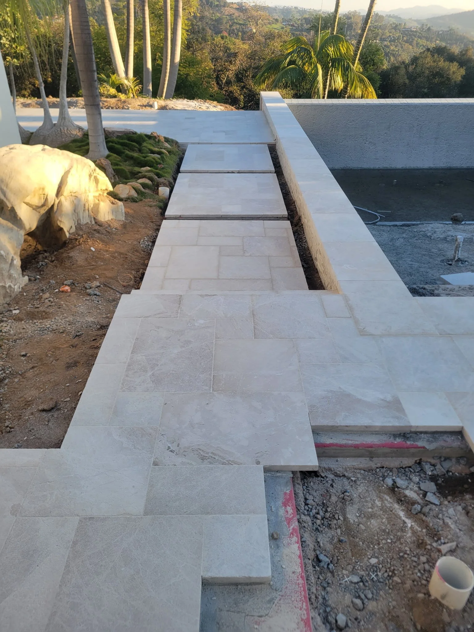 Custom poolside walkway with connecting steps designed to create a smooth and safe transition around the backyard pool area, professionally installed by our hardscape team.