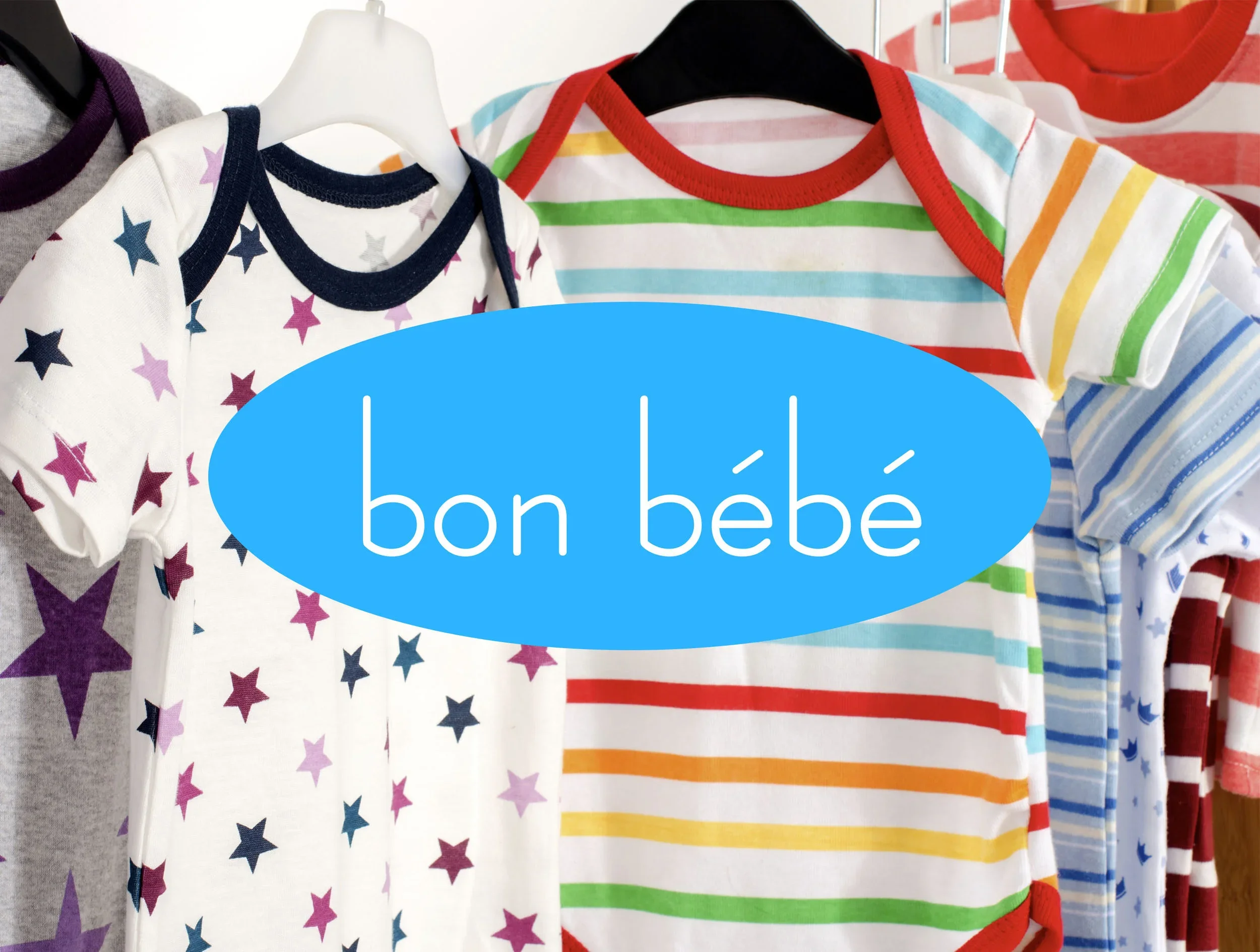 Colorful children's clothing with striped and star patterns on display, with a blue oval overlay containing the words "bon bébé."