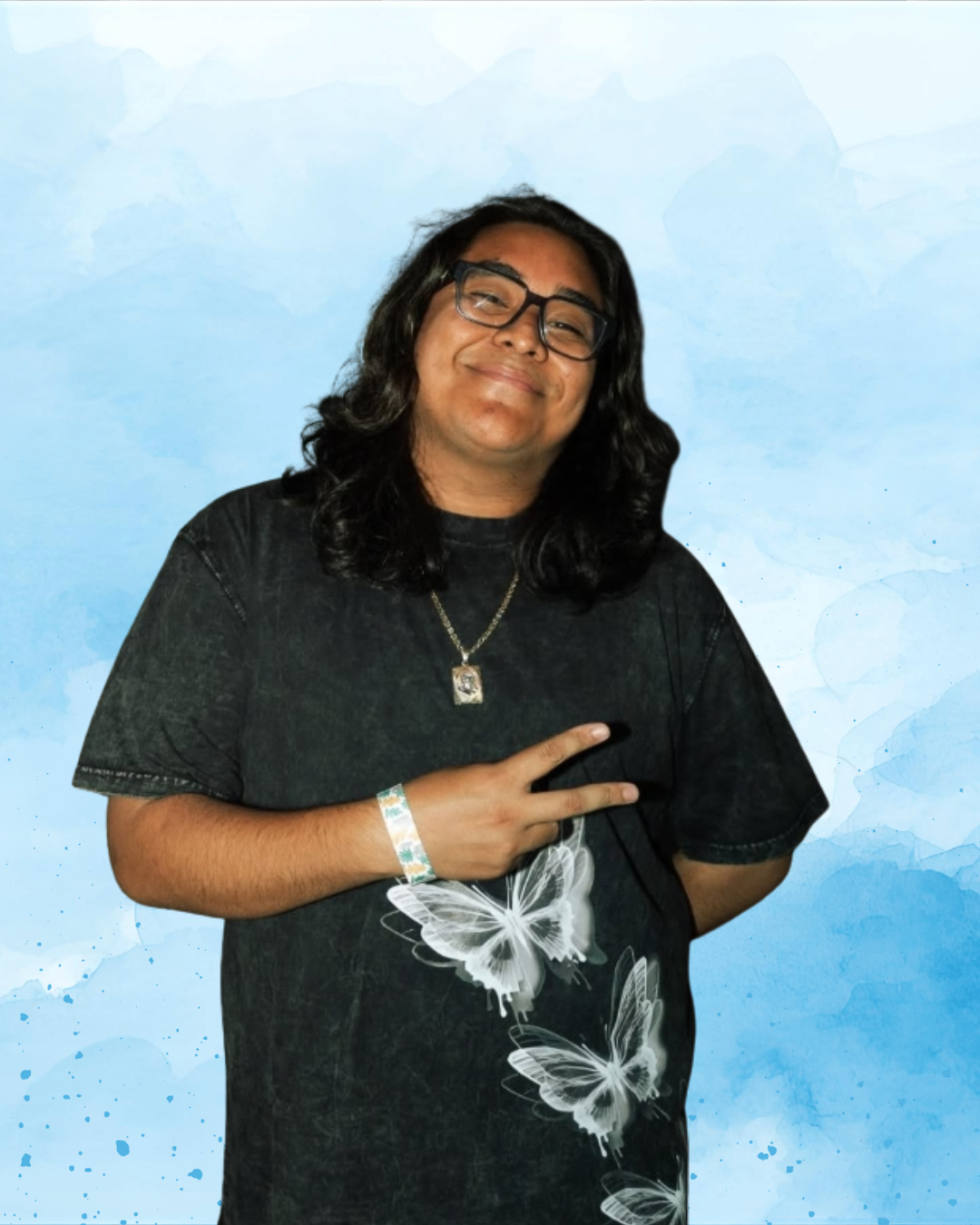 A person with long dark hair, glasses, wearing a black T-shirt with butterfly designs, making a peace sign with their right hand, against a blue watercolor background.