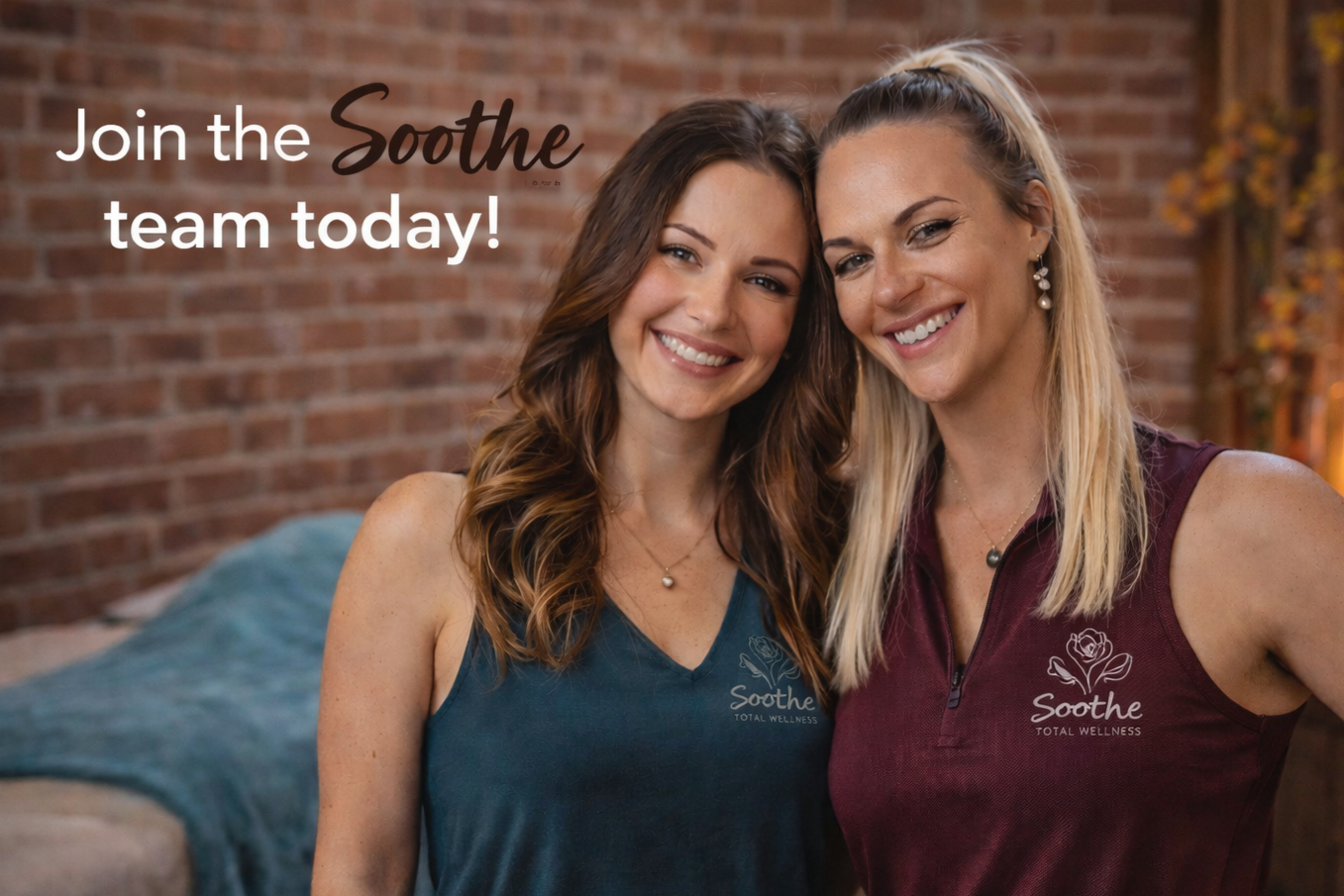 Two smiling women with long hair, one with dark brown and one with blonde, wearing sleeveless workout shirts with the Soothe logo, standing close together in front of a brick wall.