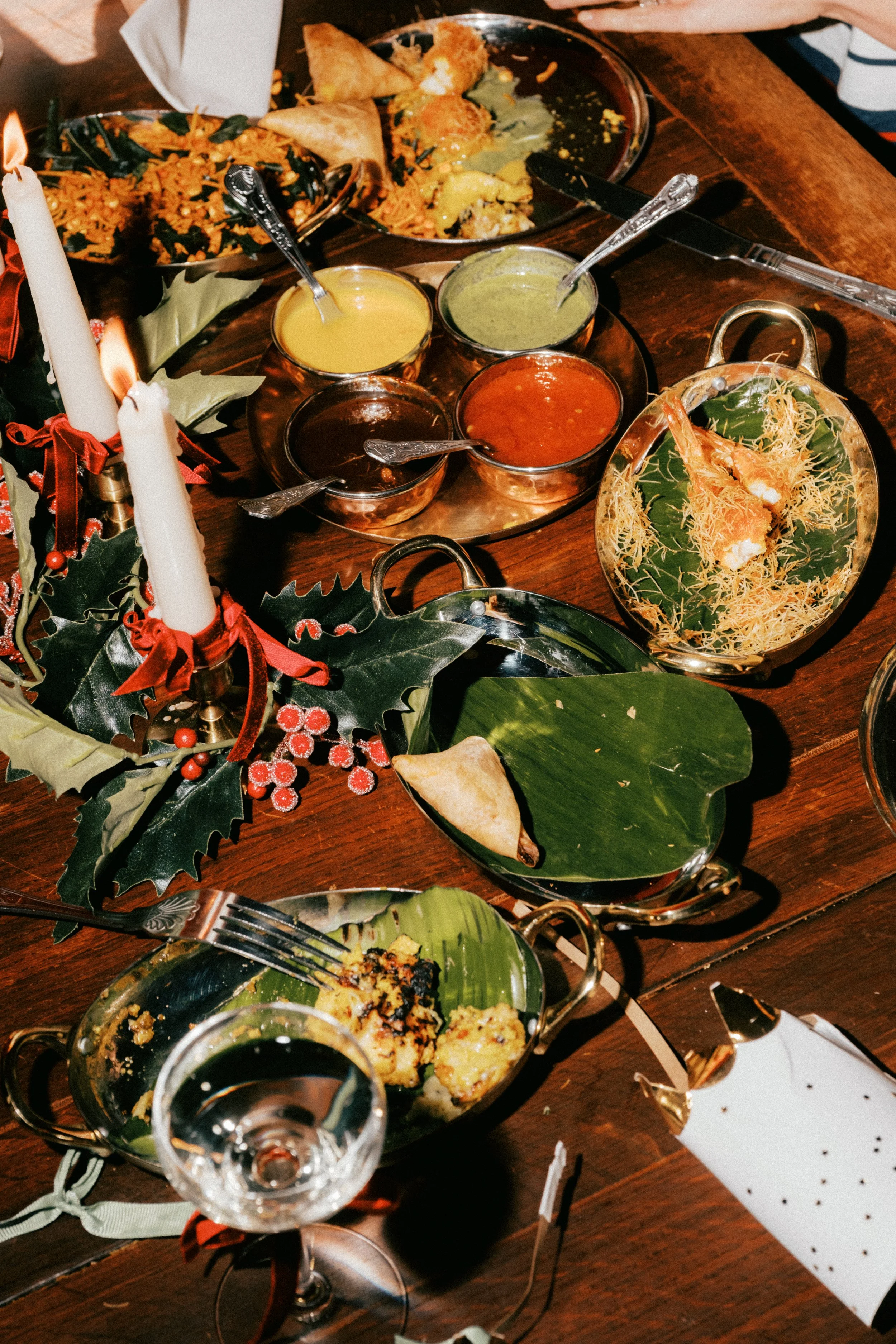 A festive holiday dinner table with partially eaten food, candles, and Christmas decorations.
