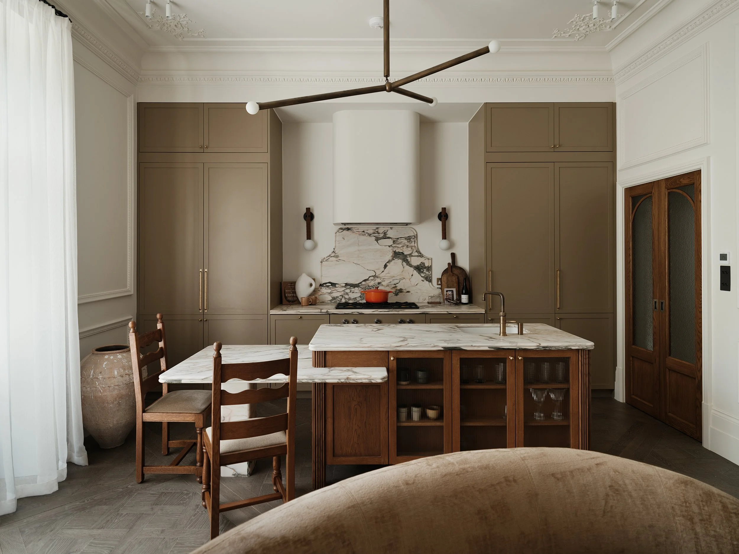 Modern kitchen with beige cabinets, white marble countertops, wooden kitchen island, and decorative lighting fixtures.