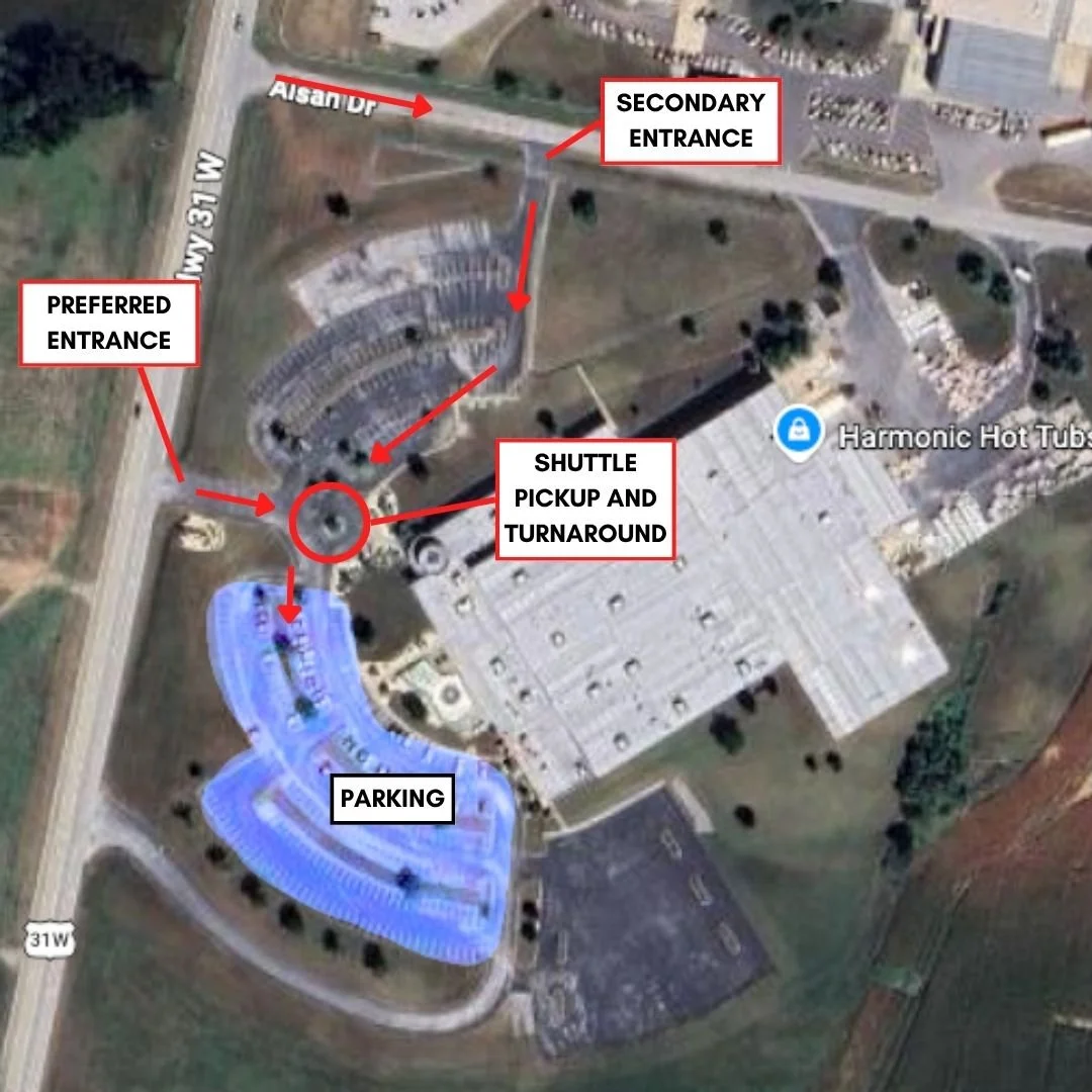 Aerial view of a facility with labeled entrances, shuttle pickup area, parking lot, and surrounding roads. The preferred entrance is on the left side off Highway 31 W, and the secondary entrance is at the top. There is a shuttle pickup and turnaround point near the center, parking area colored in blue at the bottom, and a building with an outdoor hot tub area labeled 'Harmonic Hot Tubs.'