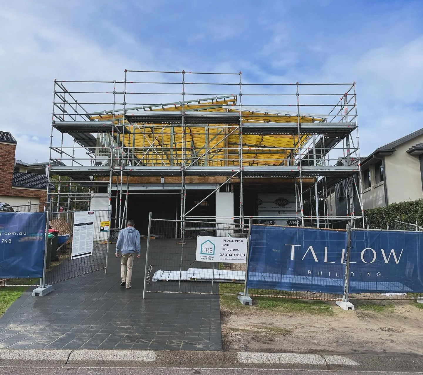 Home renovation in Redhead, NSW, showing a two-story building with scaffolding, site fencing, and a Tallow Building sign.